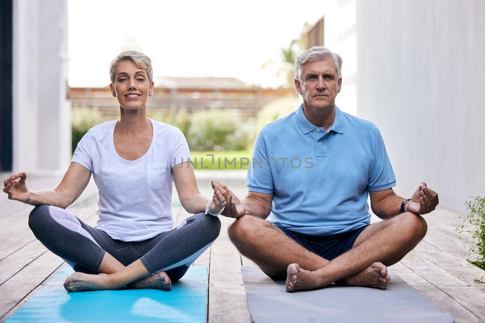 Yoga keeps mind and body sharper. Shot of a mature couple meditating together outdoors. by YuriArcurs