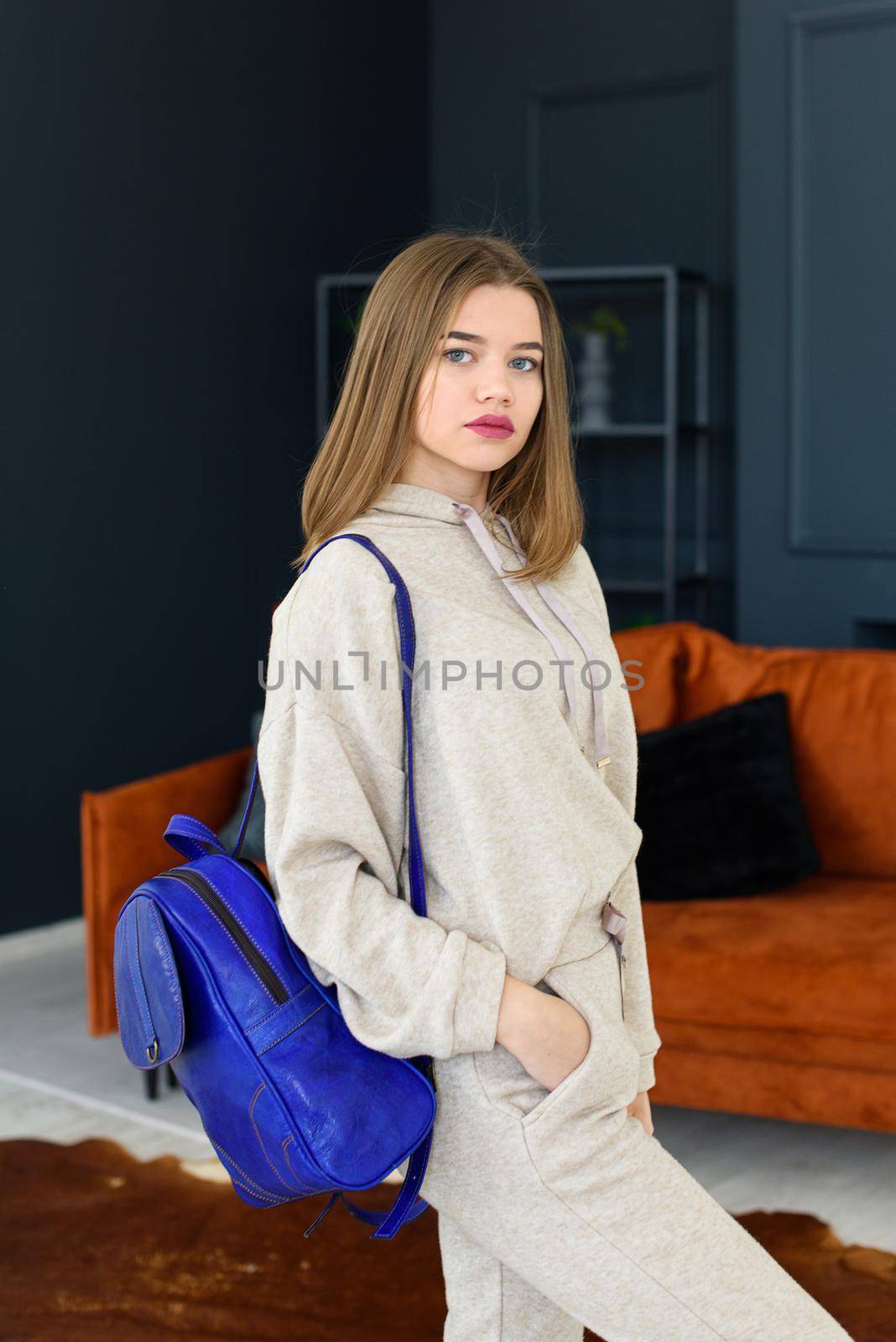 photo of a women in beige sports suit and blue leather backpack posing in a hotel room. selective focus by Ashtray25