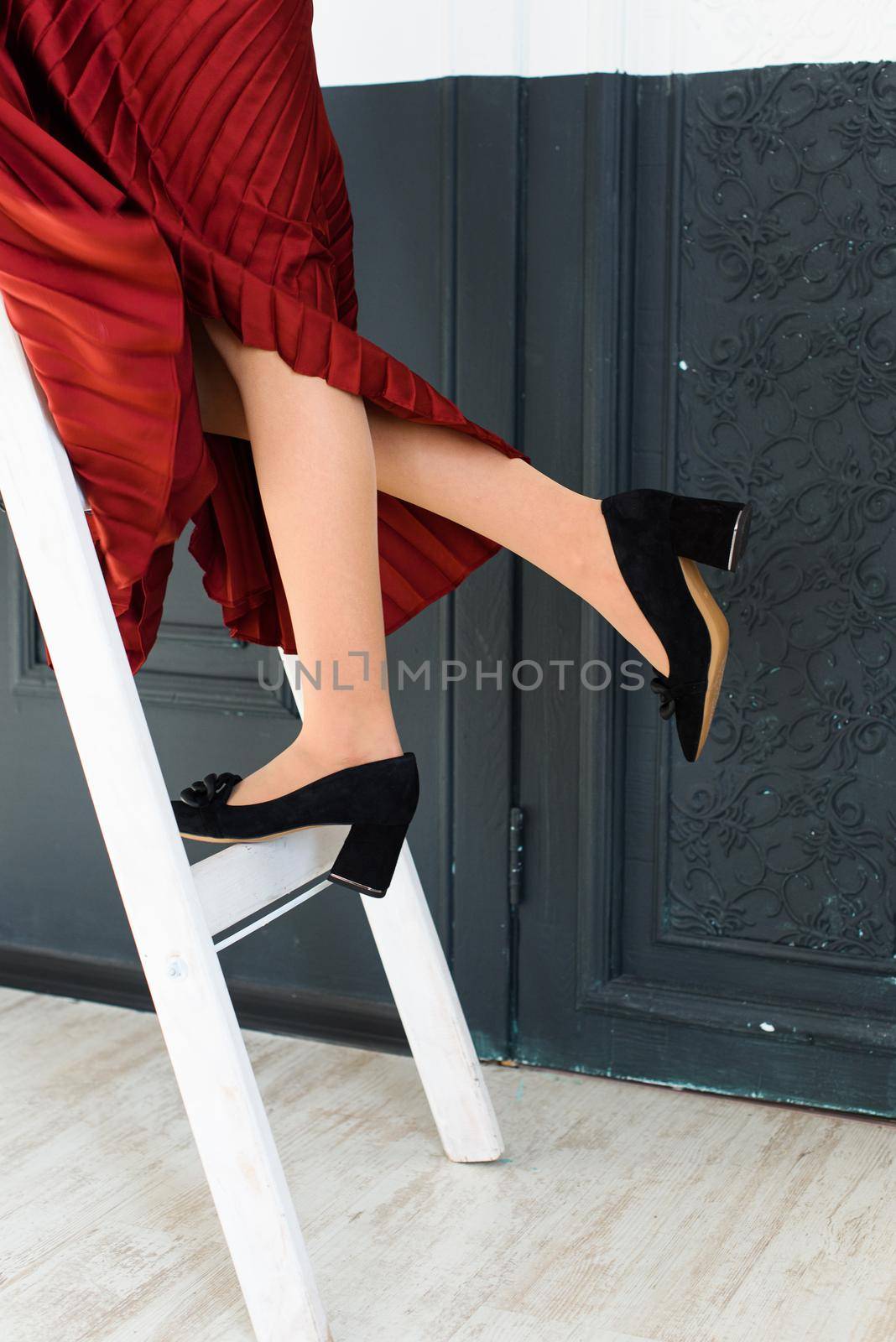 Photo of a womens legs in suede high-heeled shoes with a buckle. Selective focus