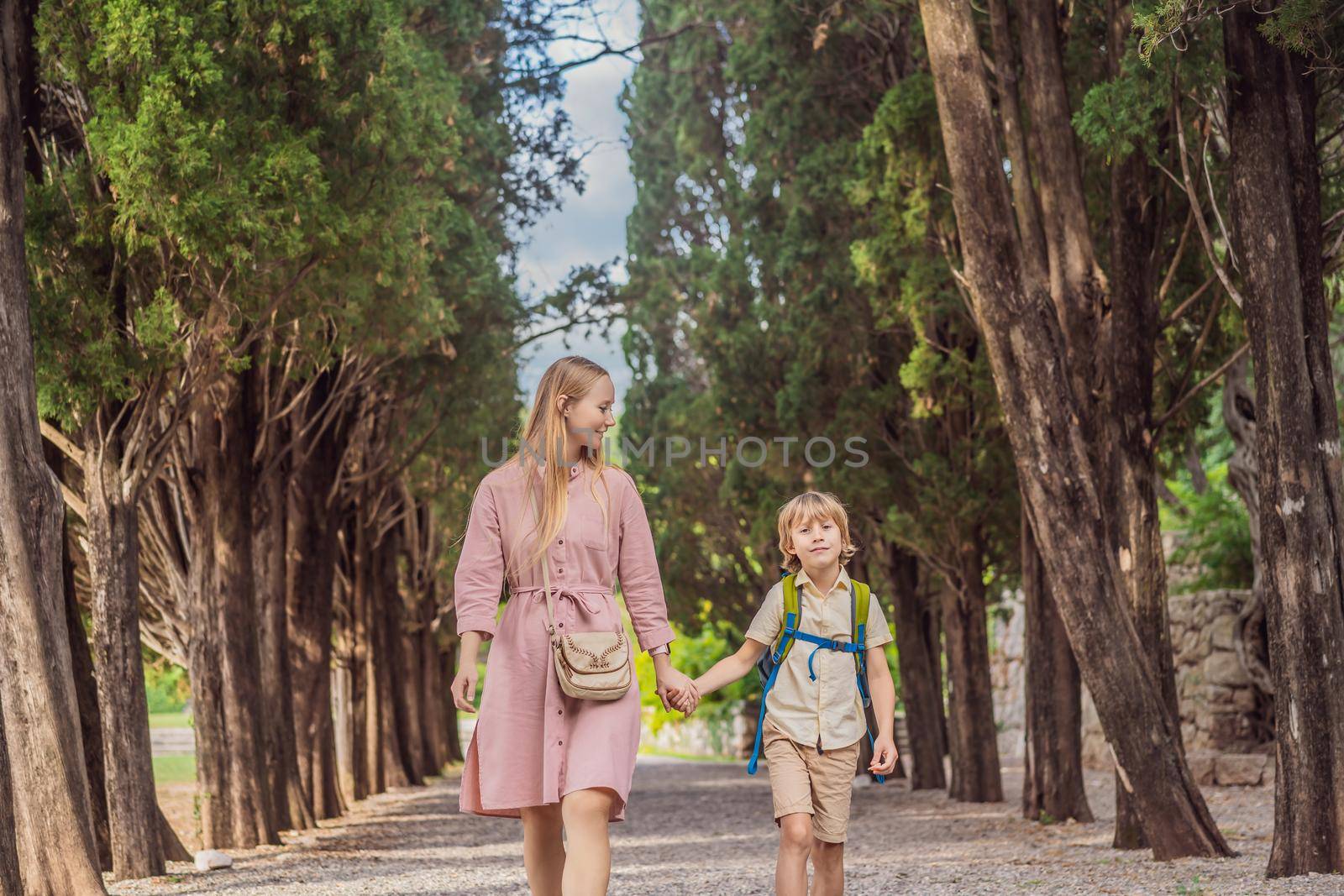 Mom and son tourists walking together in Montenegro. Panoramic summer landscape of the beautiful green Royal park Milocer on the shore of the the Adriatic Sea, Montenegro.