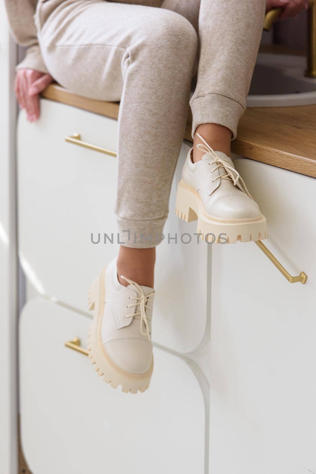 Part photo of a women in beige sports suit and stylish leather oxfords shoes posing on the kitchen. selective focus by Ashtray25