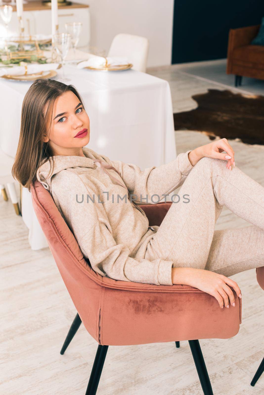 photo of a women in beige sports suit posing in the chair on a kitchen . selective focusIndoors