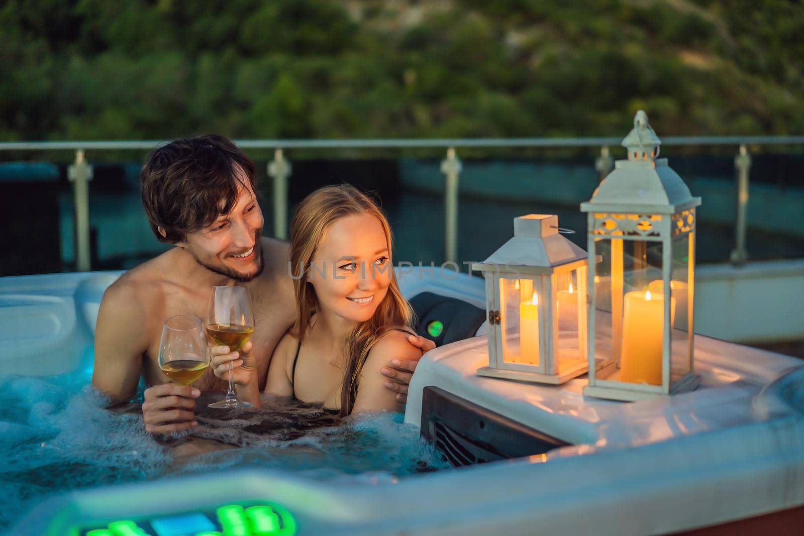 Portrait of young carefree happy smiling couple relaxing at hot tub during enjoying happy traveling moment vacation life against the background of green big mountains.