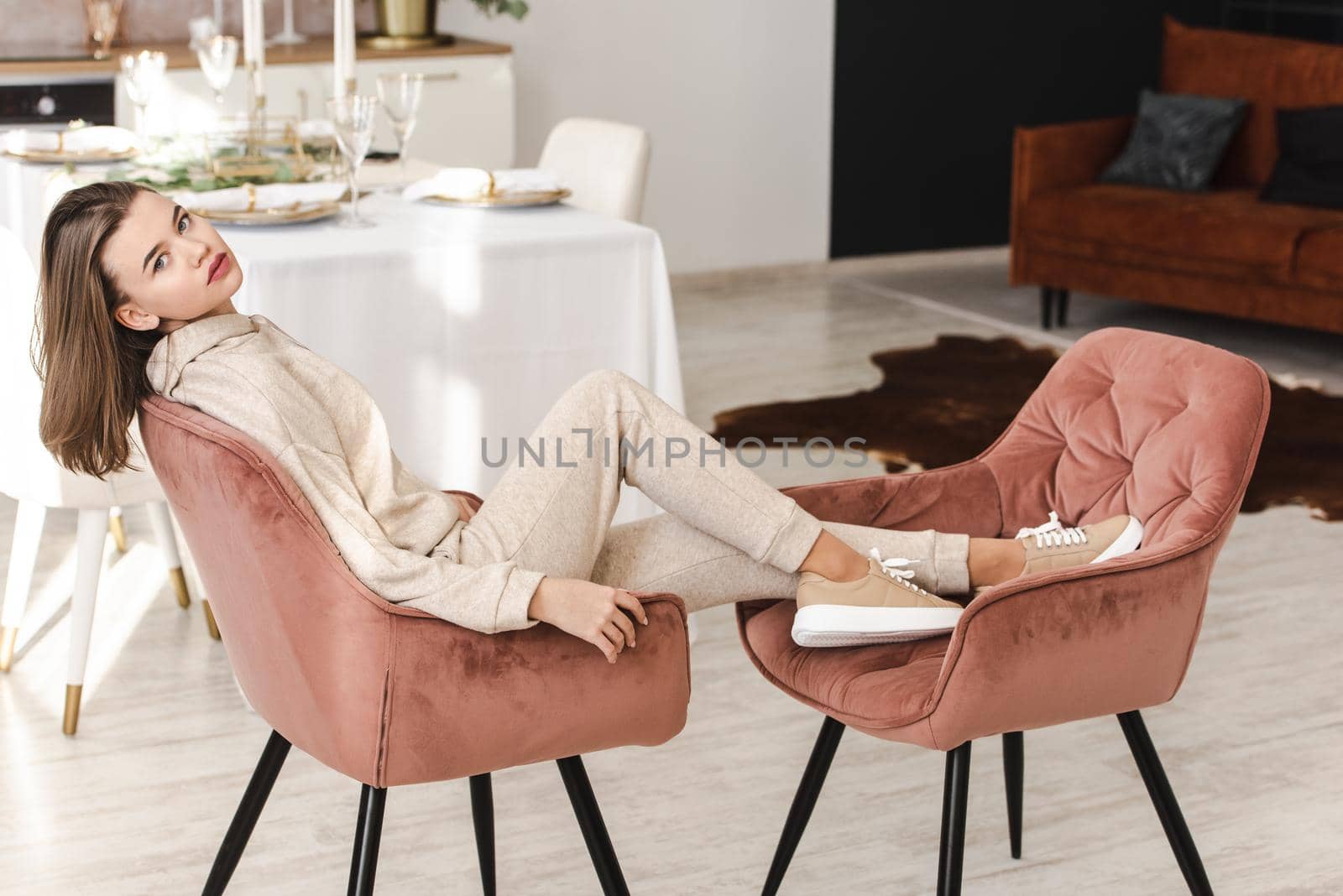 photo of a women in beige sports suit and stylish leather sneakers posing in the chair on a kitchen . selective focus by Ashtray25