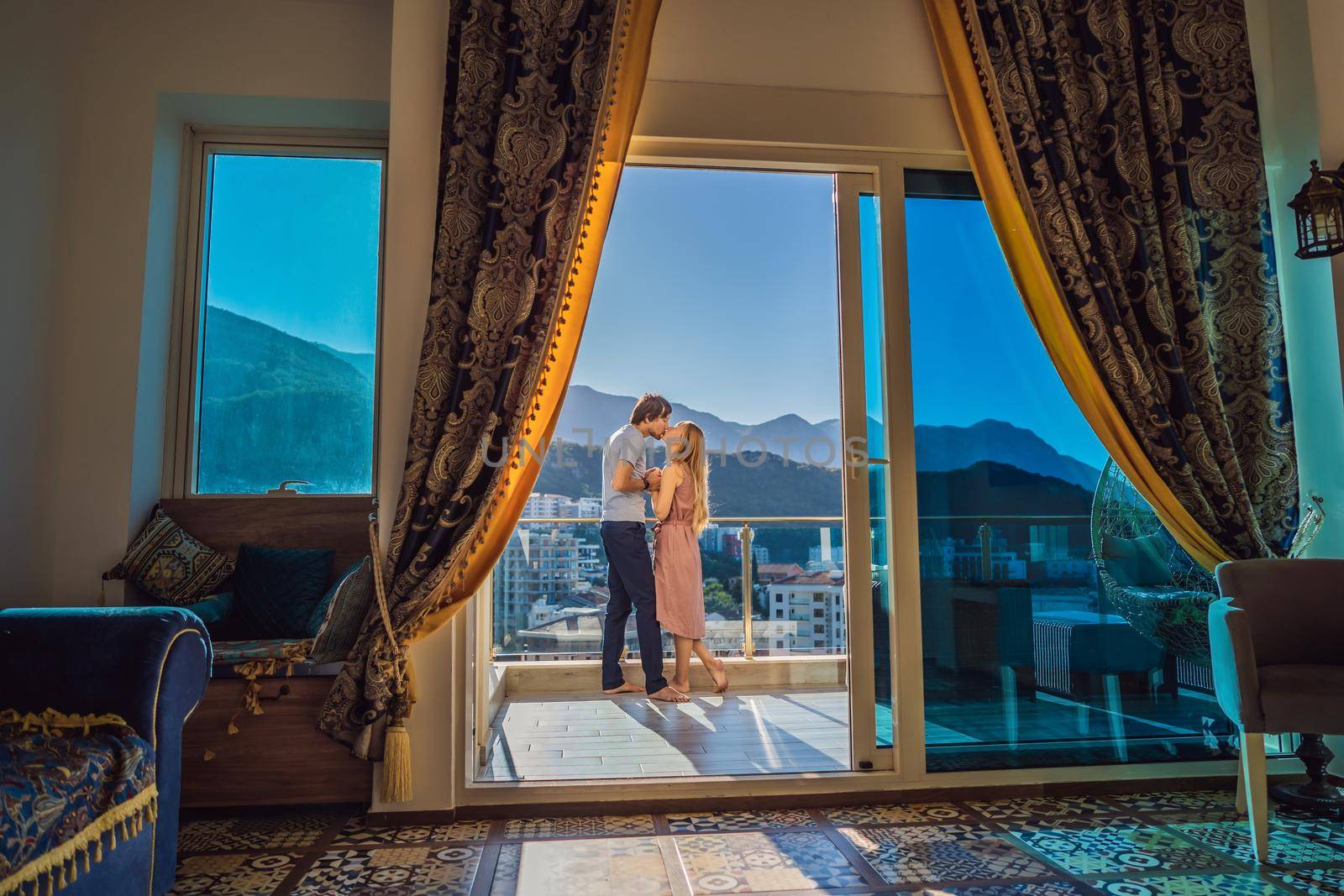 Couple on the balcony against the backdrop of mountains and city, Montenegro. life terrace pretty happiness summer home. Inspiration city romantic hotel.