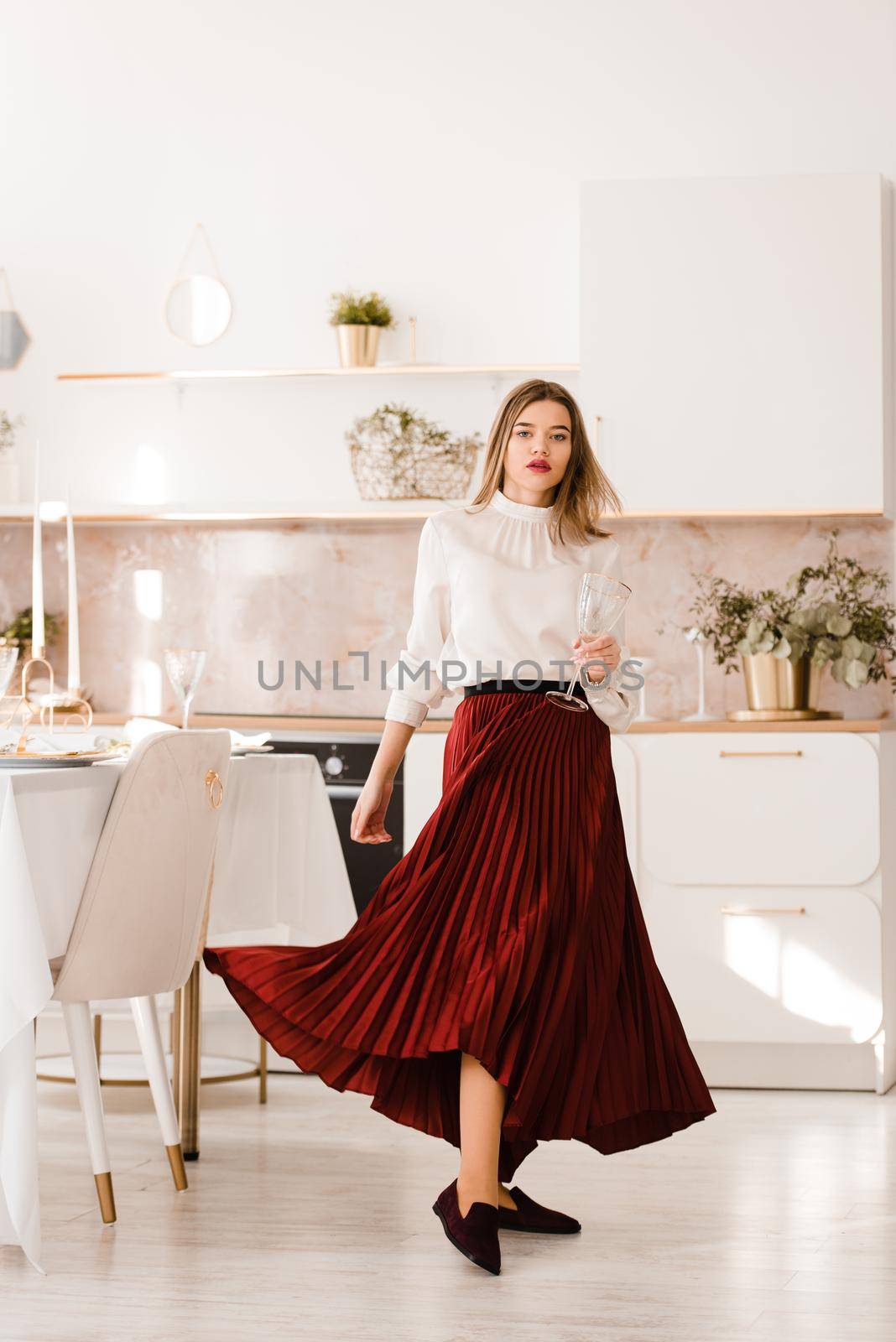 Portrait of fashionable woman in a red skirt, white blouse and stylish suede shoes with a buckle posing on the kitchen. by Ashtray25