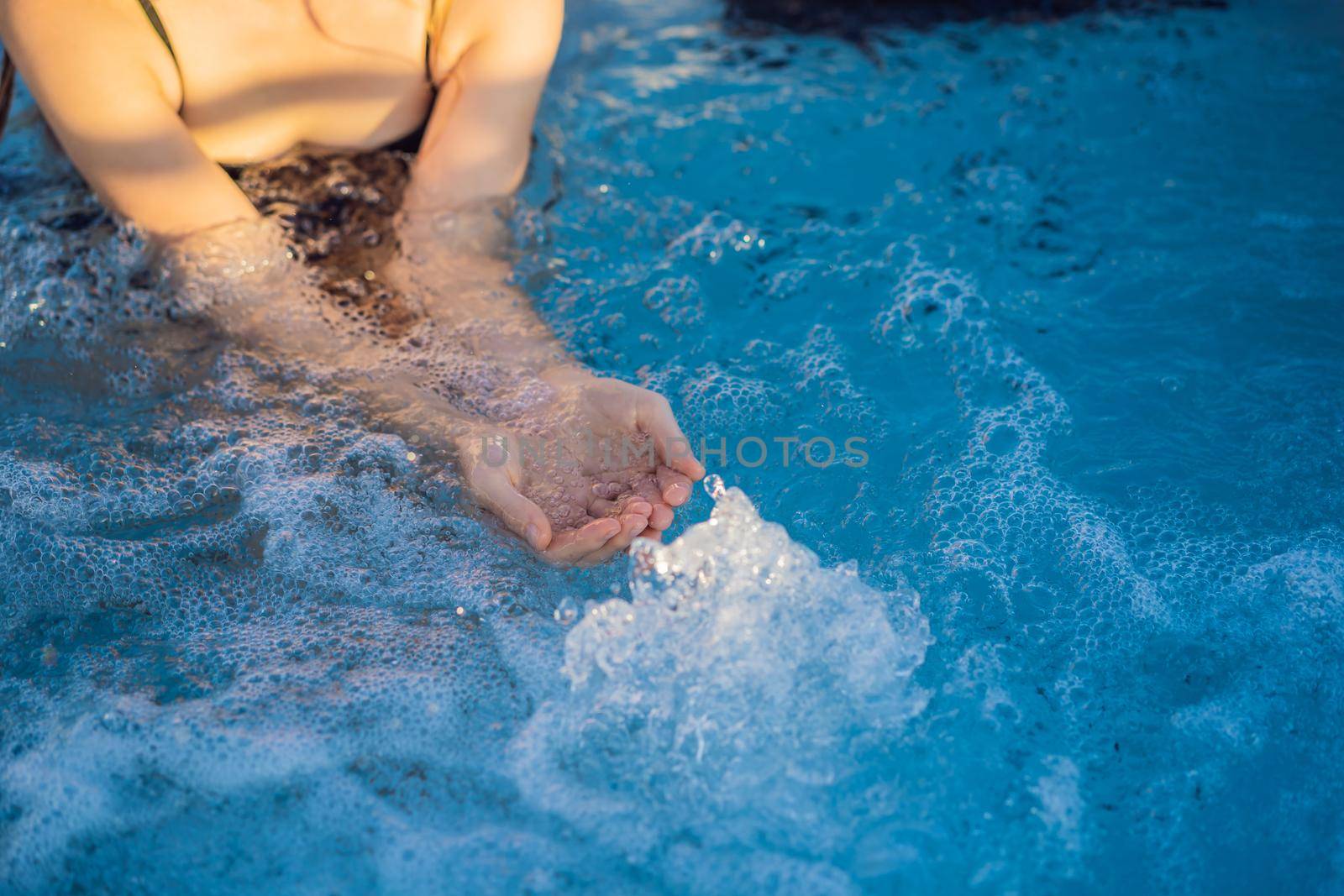 Portrait of young carefree happy smiling woman relaxing at hot tub during enjoying happy traveling moment vacation life against the background of green big mountains.