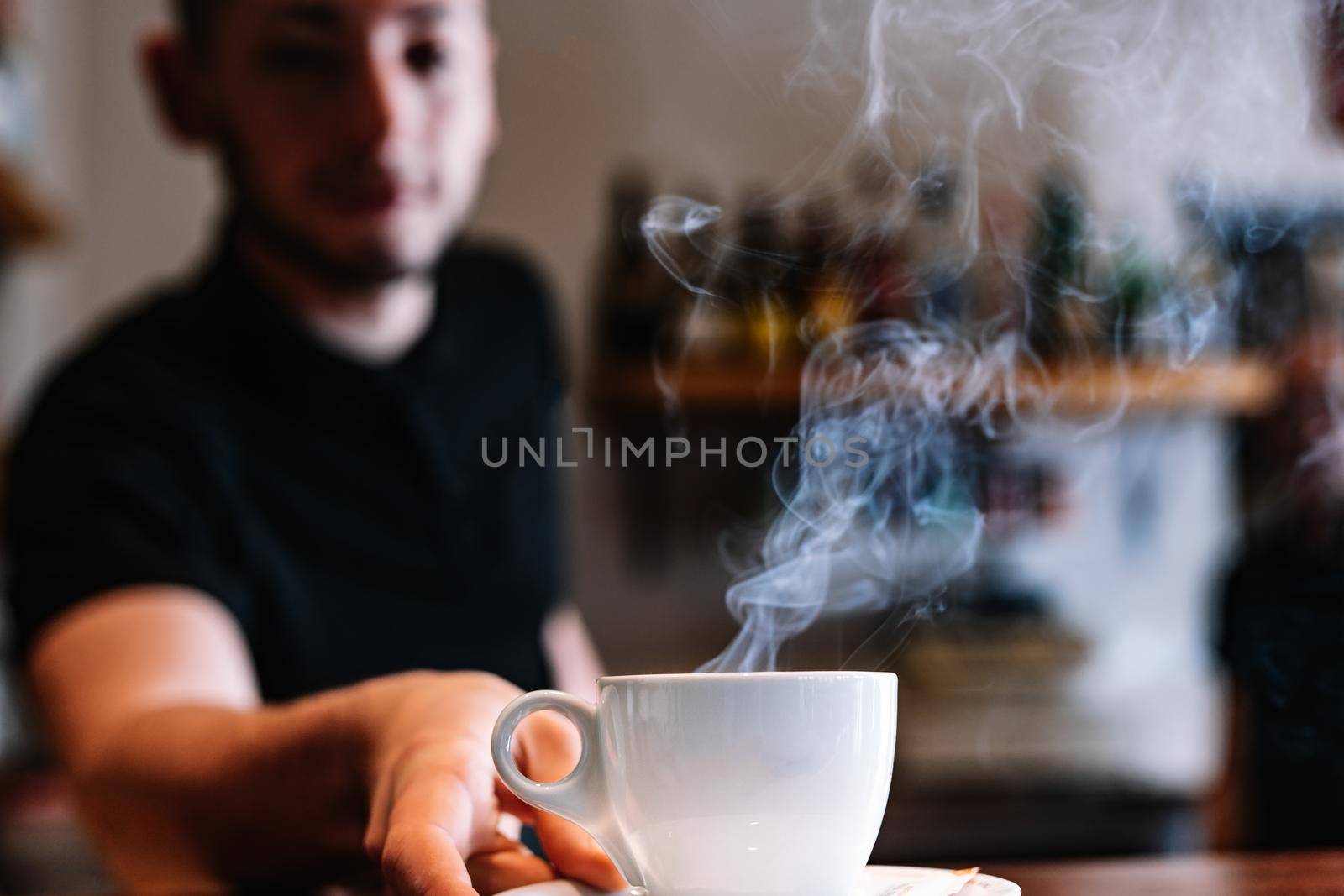 Close-up of a cup of coffee on a bar counter. Waiter serving coffee at the counter of a coffee shop. by CatPhotography