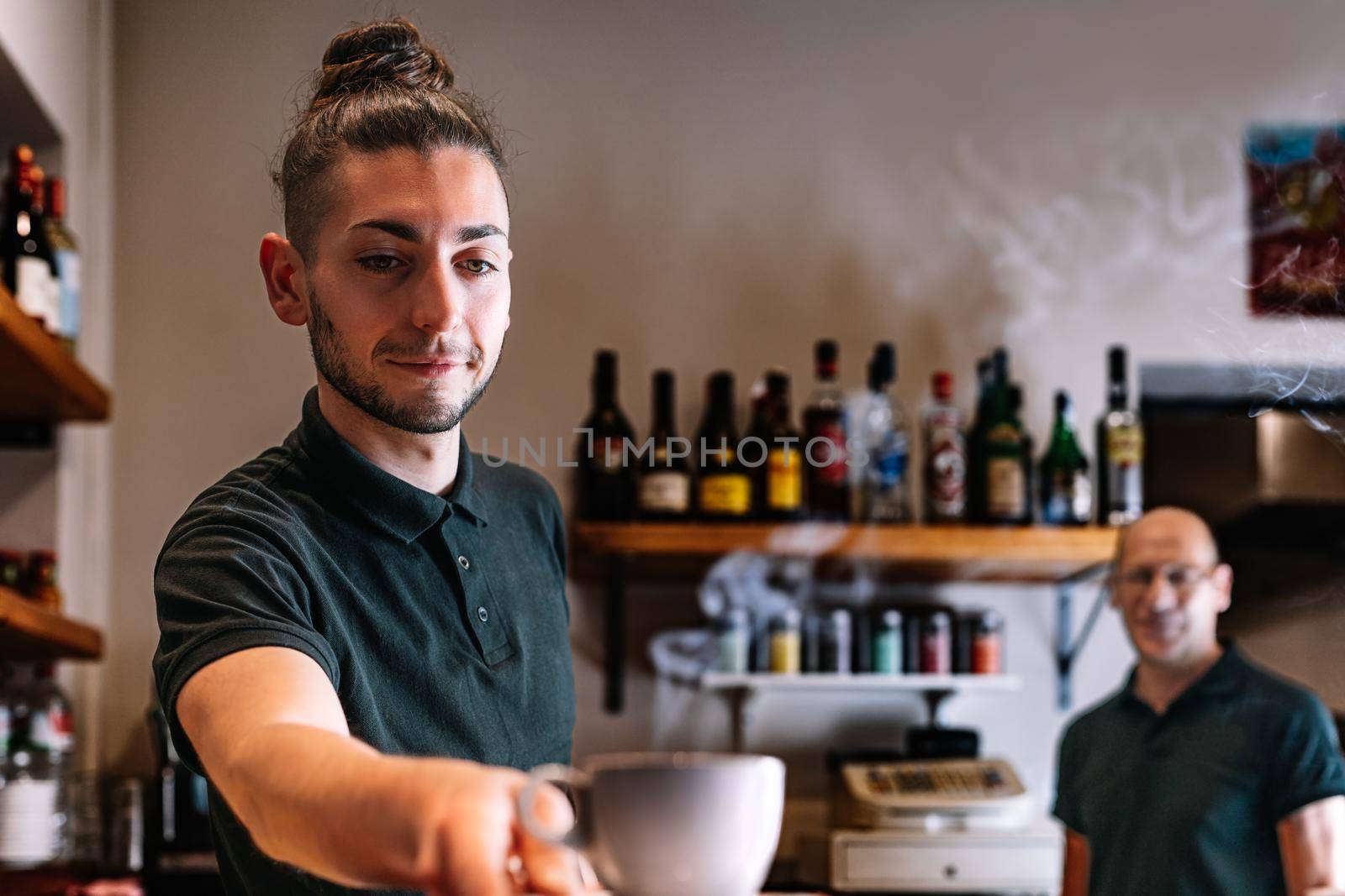 Young waiter serving a cup of coffee on a bar counter. worker serving a coffee to a customer by CatPhotography