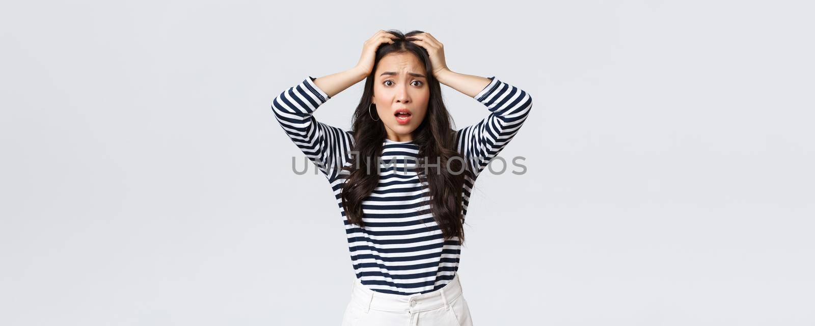 Lifestyle, people emotions and casual concept. Troubled young woman stare alarmed, feel bad as something awful happened, grab head and stare camera anxious, white background.