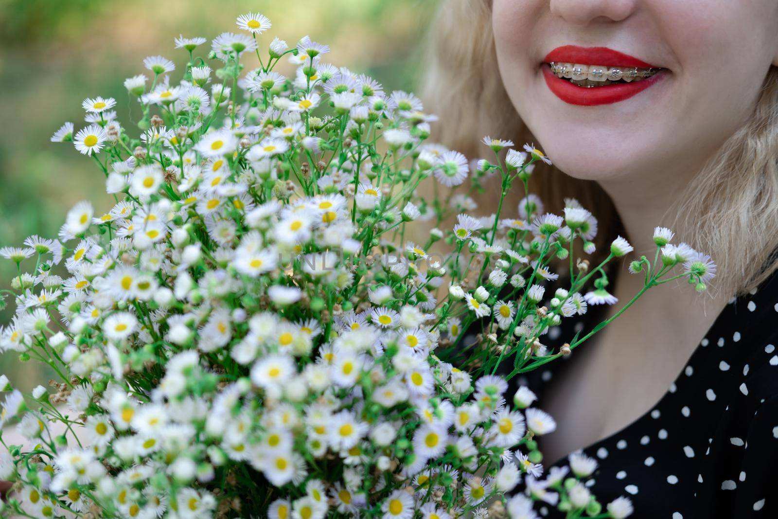 portrait of a charming blonde teenage girl wearing teeth braces with bouquet of white wildflowers. female with braces in mouth. healthy teeth. orthodontist dentist by oliavesna