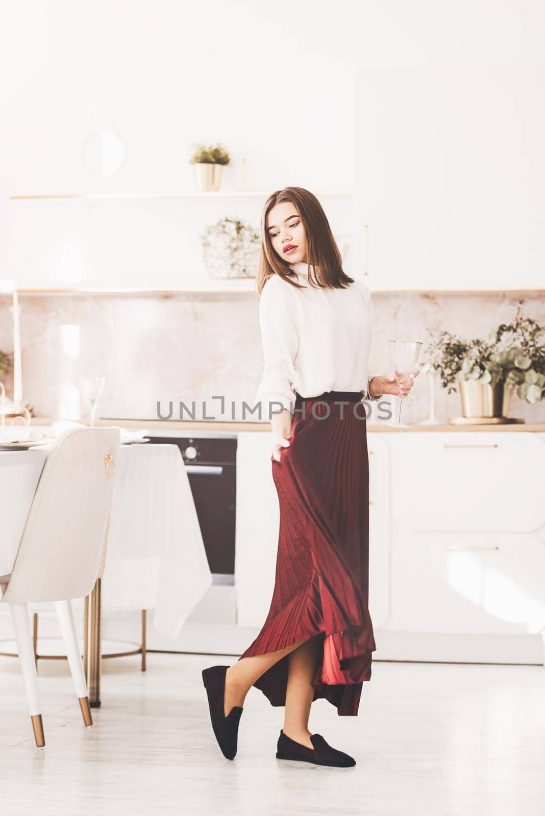 Portrait of fashionable woman in a red skirt, white blouse and stylish suede shoes with a buckle posing on the kitchen. by Ashtray25