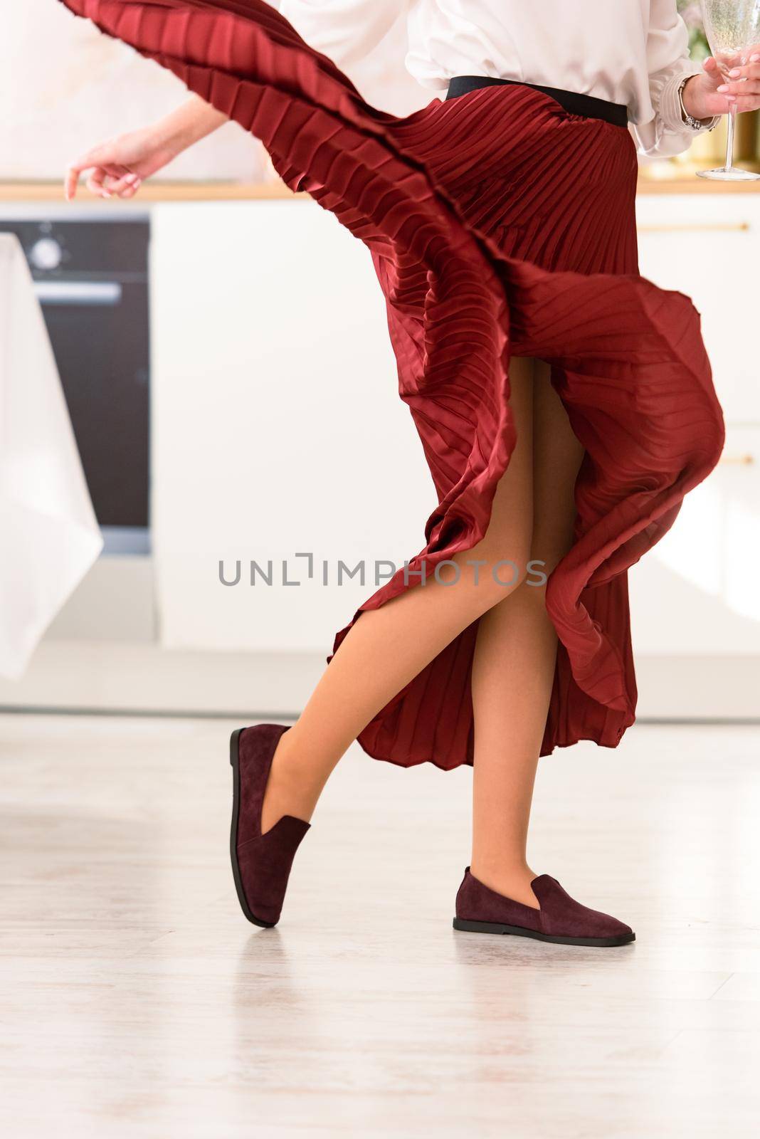 Photo of women's legs in a stylish suede burgundy loafers. Woman wearing red skirt