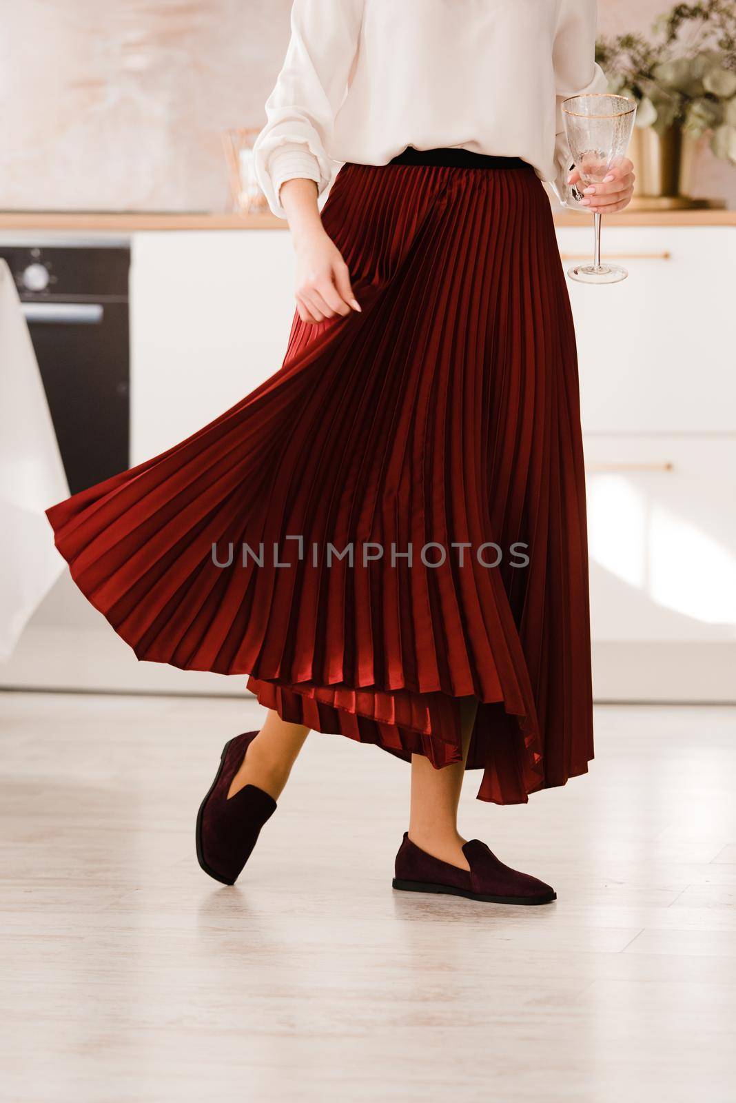 Photo of women's legs in a stylish suede burgundy loafers. Woman wearing red skirt