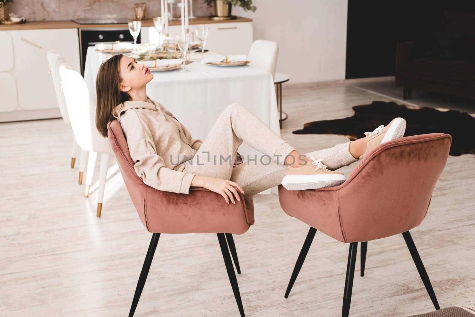 photo of a women in beige sports suit and stylish leather sneakers posing in the chair on a kitchen . selective focus by Ashtray25