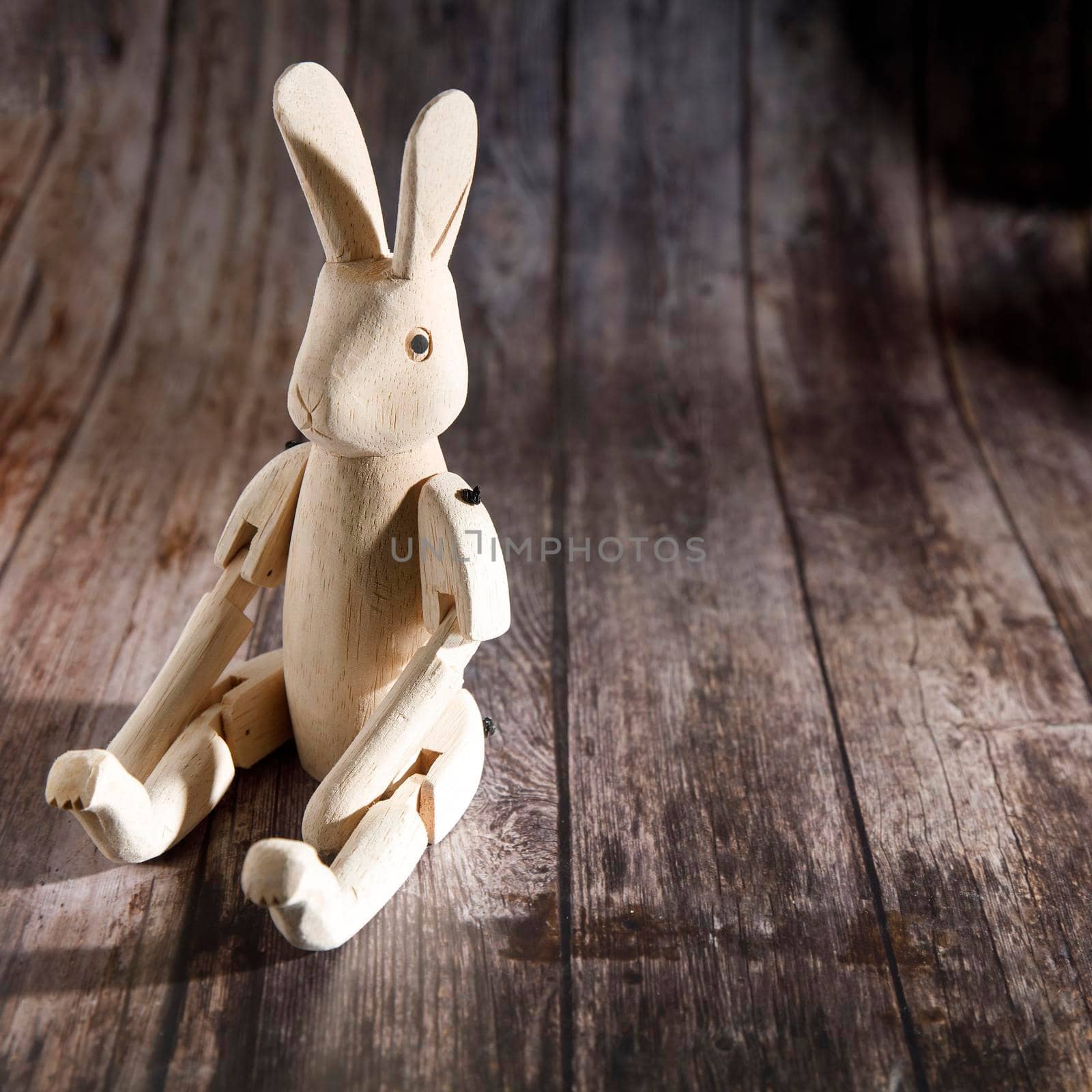 Raw wood hinged hare on a wooden table. Easter decoration. Copy space by elenarostunova