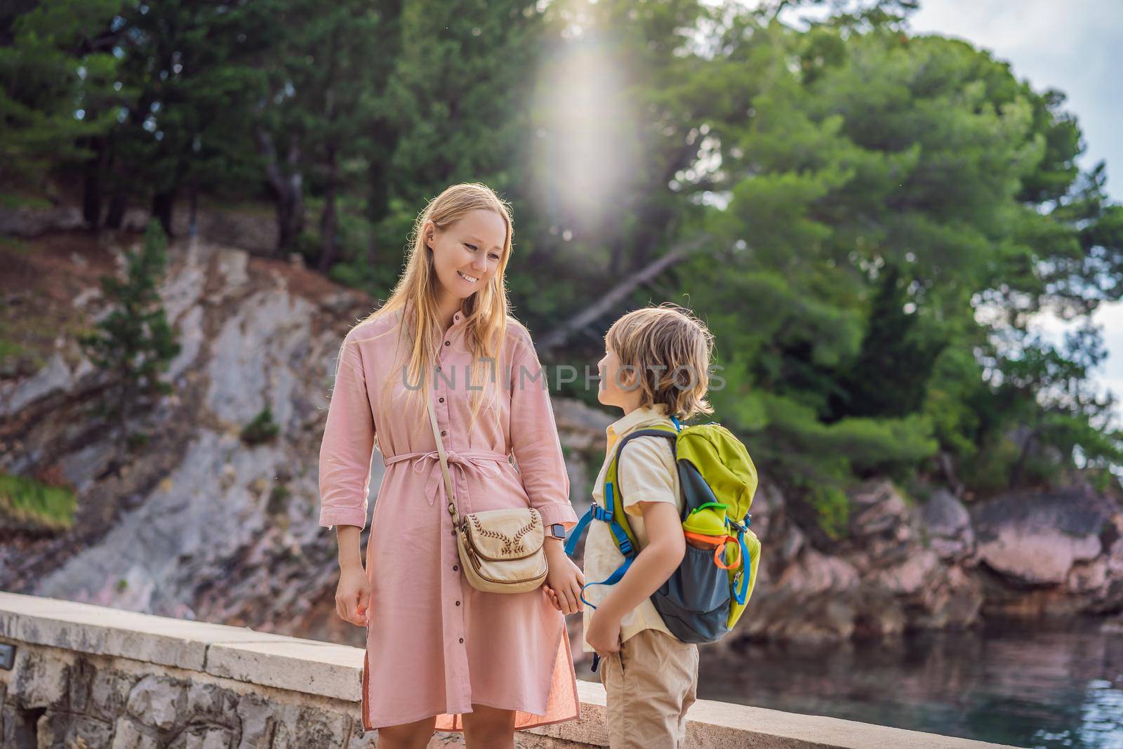 Mom and son tourists walking together in Montenegro. Panoramic summer landscape of the beautiful green Royal park Milocer on the shore of the the Adriatic Sea, Montenegro by galitskaya