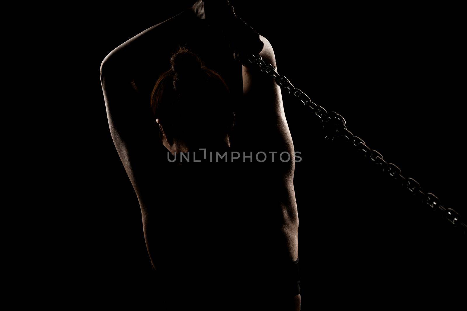 Strong fit girl with metal chain. Pulling and posing against black background