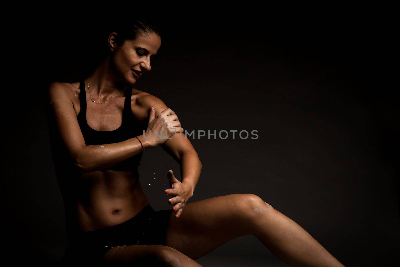 Sexy fit girl in sportswear on the ground. Magnesium powder prints of hands on her body.
