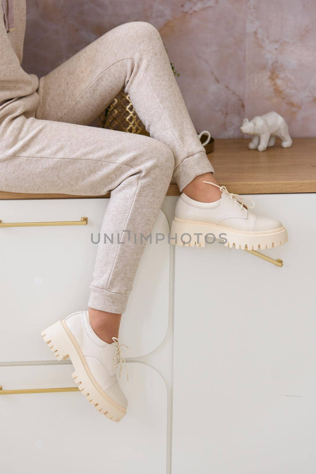 Part photo of a women in beige sports suit and stylish leather oxfords shoes posing on the kitchen. selective focus by Ashtray25