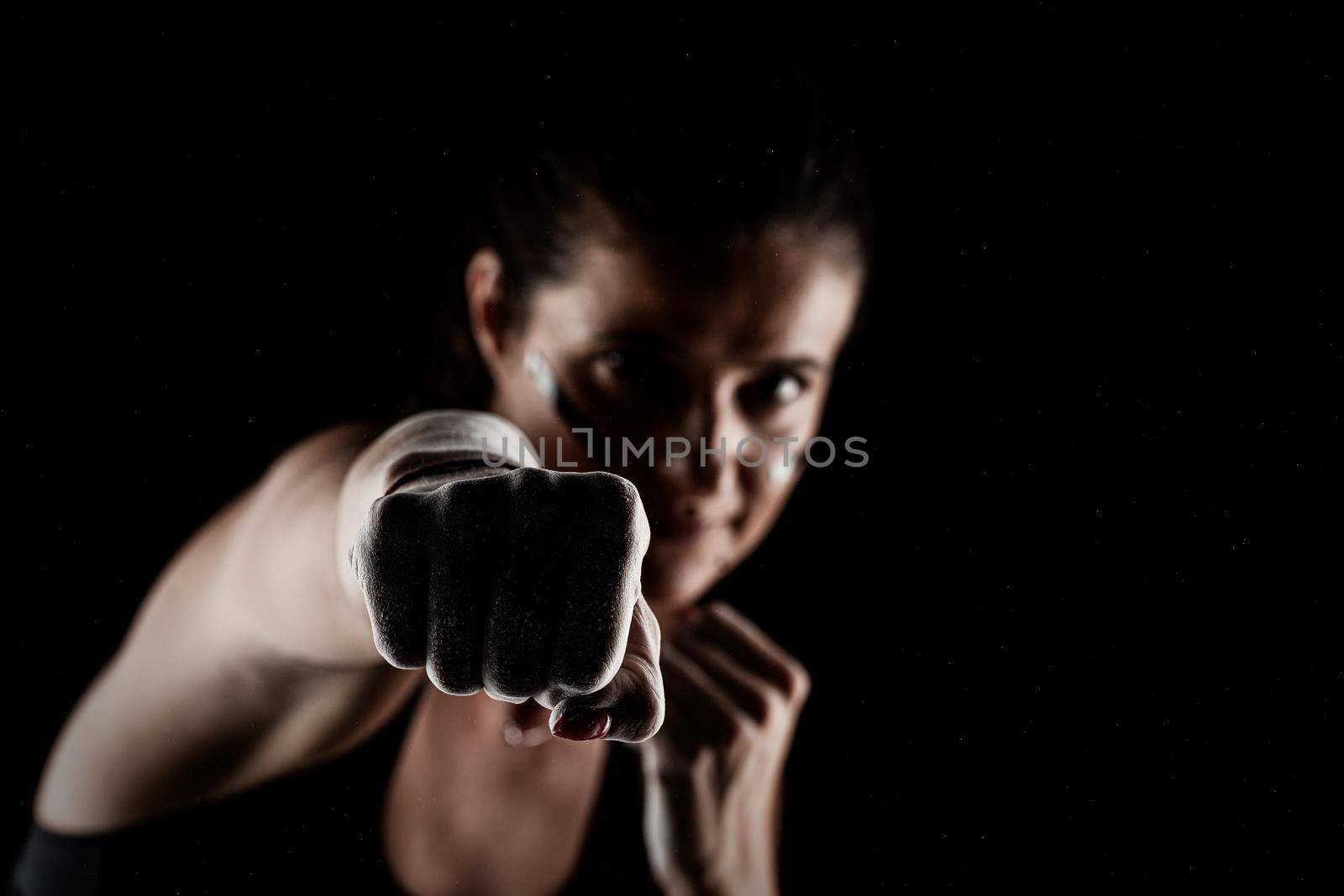 Kickboxer kirl with magnesium powder on her hands punching with dust visible.