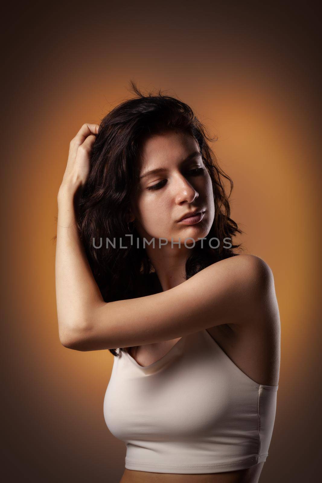 Beautiful teenage girl studio portrait on neon orange colored background.