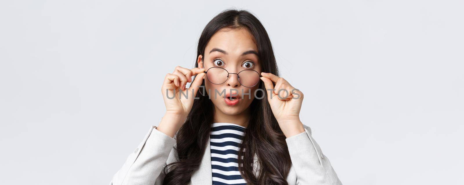 Business, finance and employment, female successful entrepreneurs concept. Close-up of surprised and impressed asian office worker take-off glass and widen eyes astonished, see awesome promo deal.