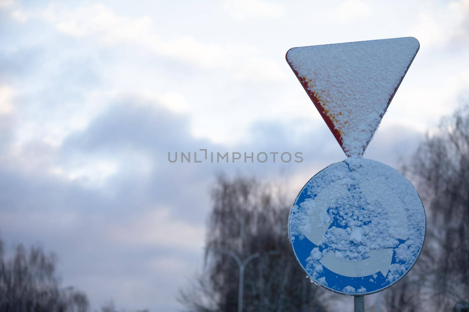 Two traffic signs, one is a traffic circle intersection or traffic circle and the other is give way.