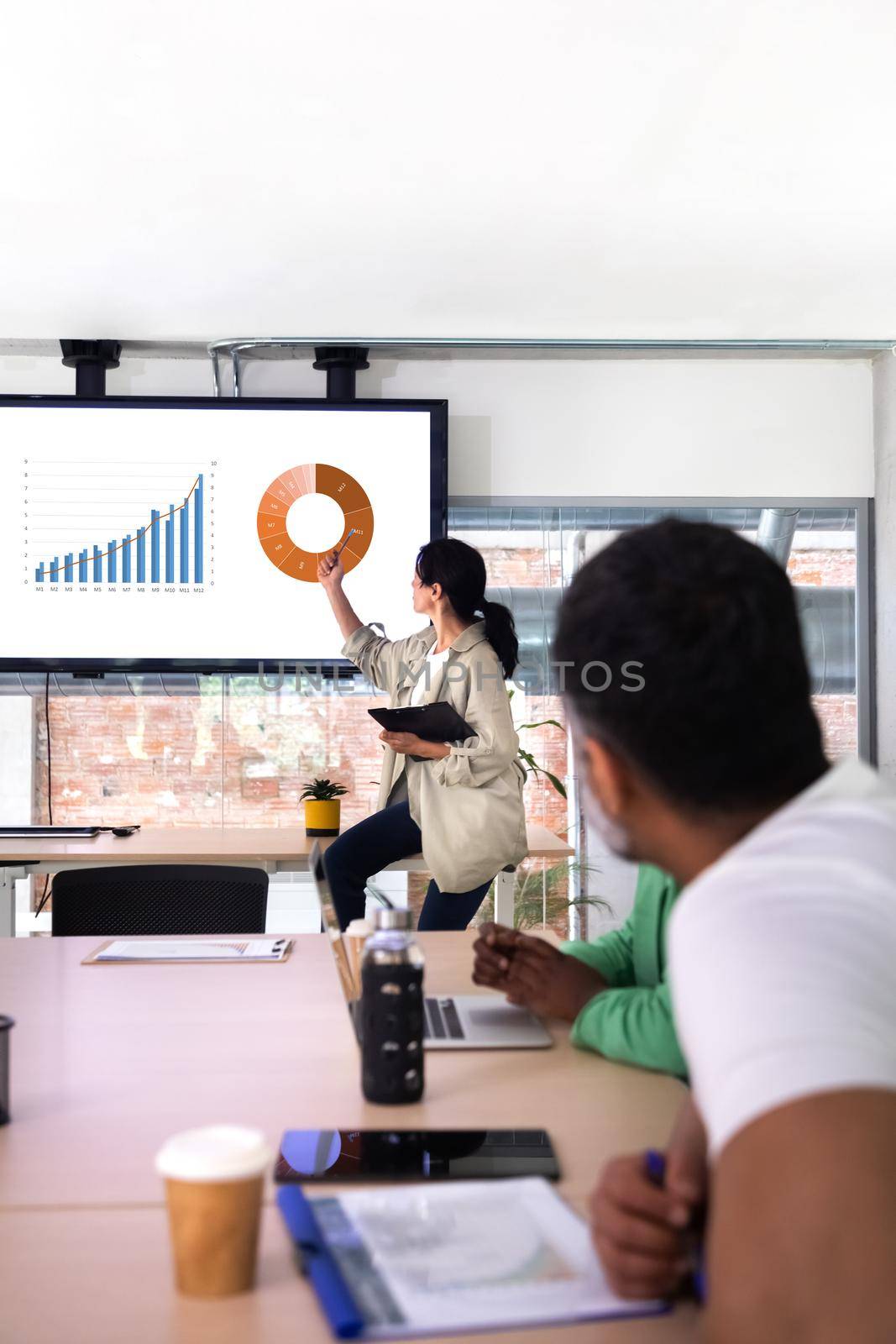 Team business meeting. Female boss looking at company results graphics. Vertical image. Business concept.