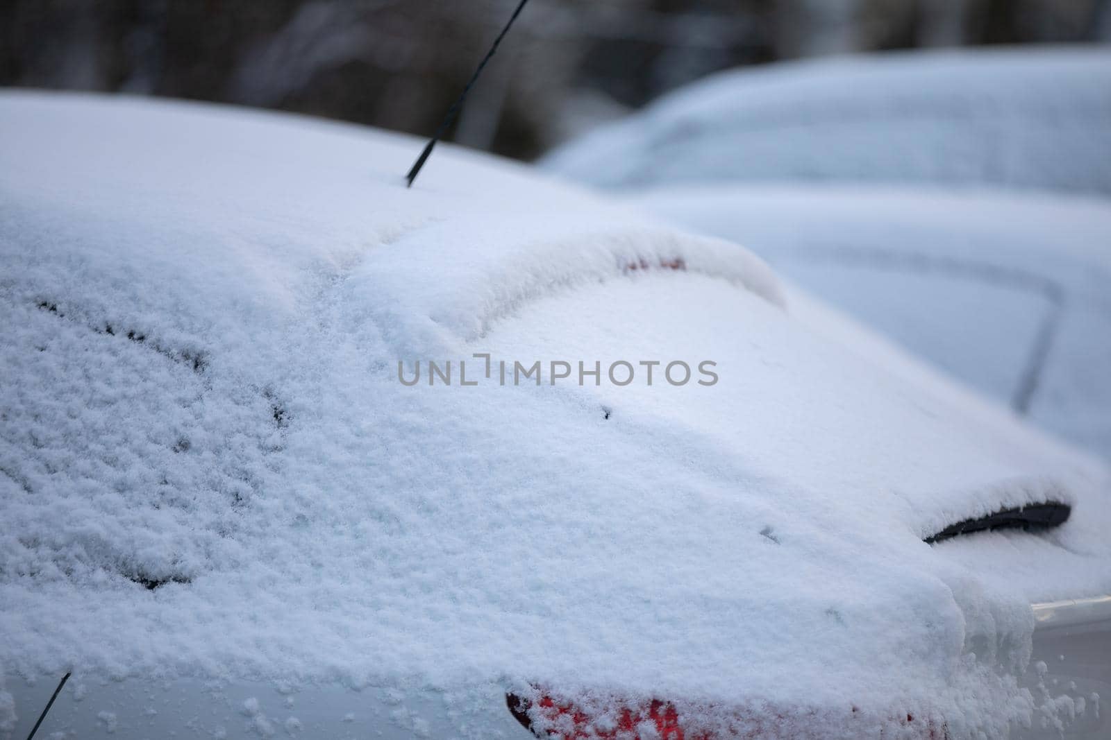 The body of the car covered with a thin layer of white snow. Winter weather is not favourable for drivers.
