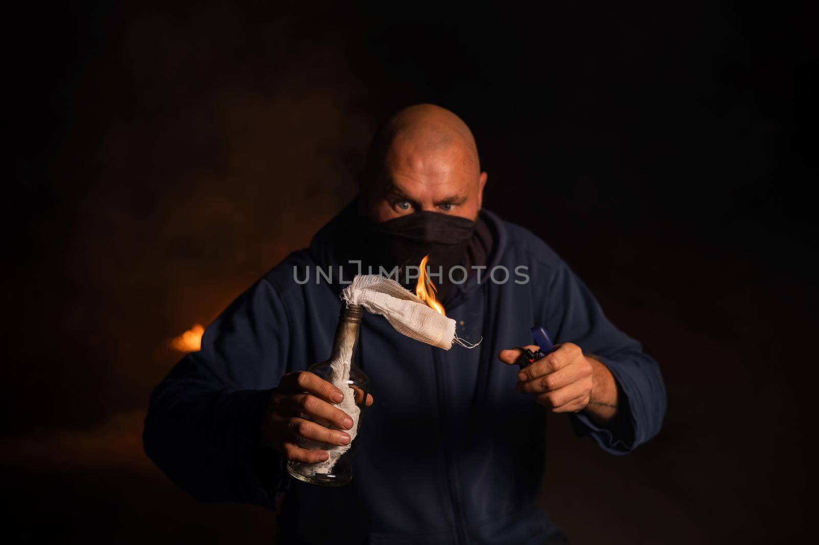 A masked man is holding a burning bottle. Molotov cocktail. by mrwed54