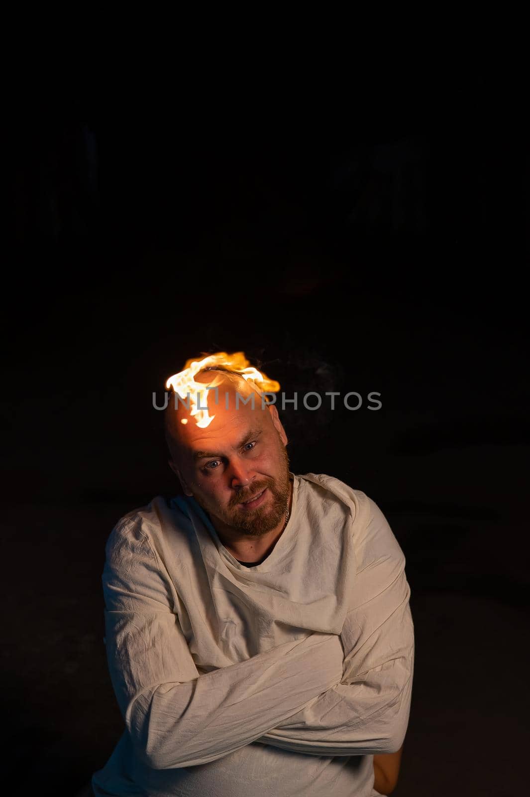 Bald man in a straitjacket with a burning head on a dark background. by mrwed54