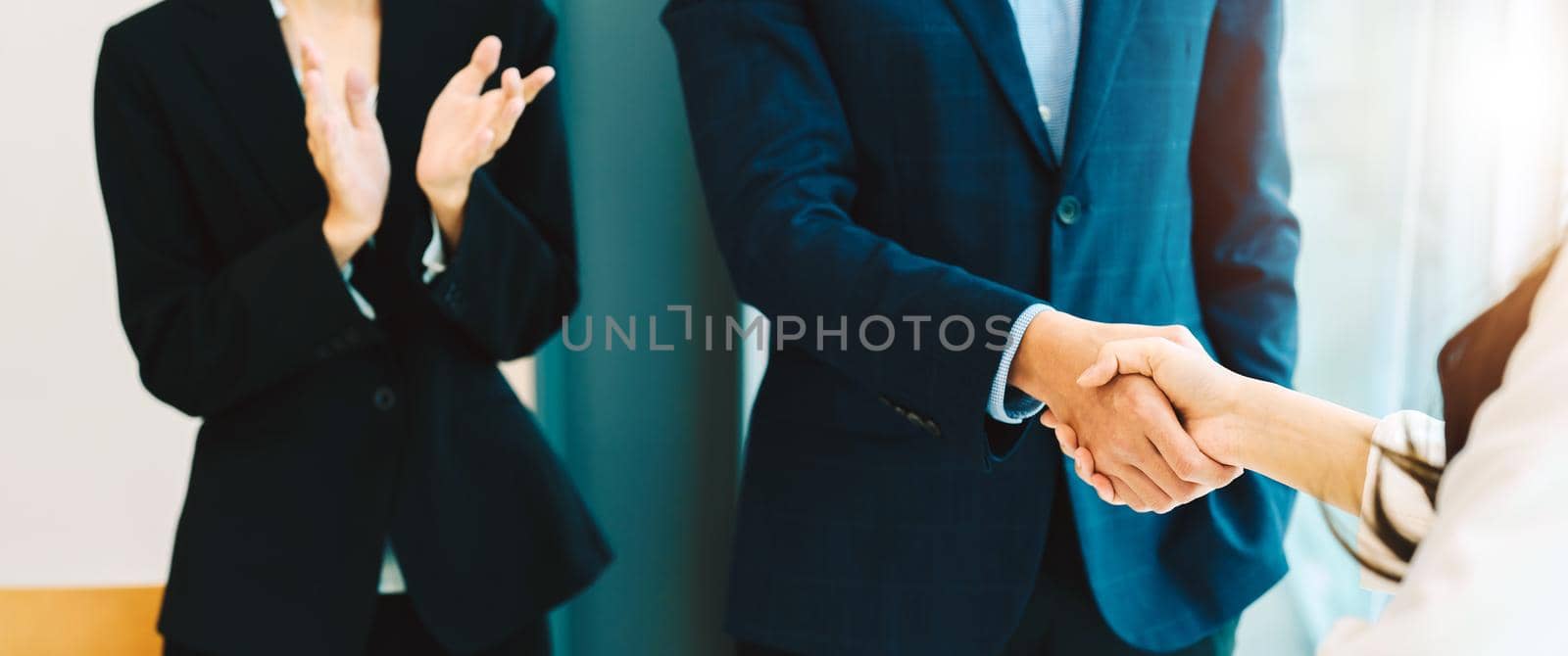 business woman applause and congrat while two business people shaking their hand after making deal or agreement. working and success Concept. by nateemee
