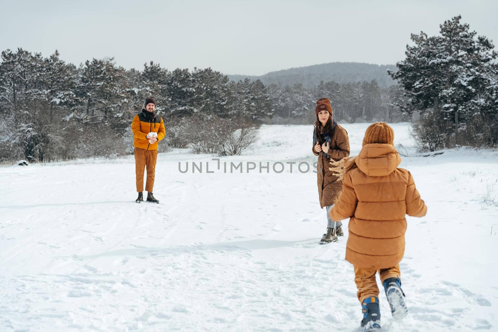Young family having fun in winter snowy forest by Fabrikasimf