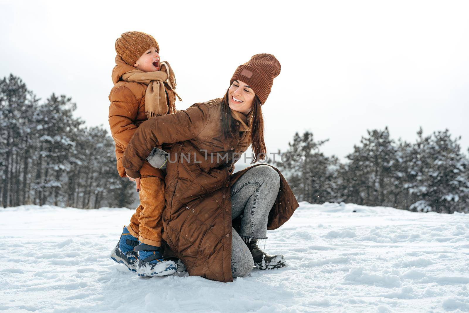 Woman with a little son on a winter hike in the snowy forest together