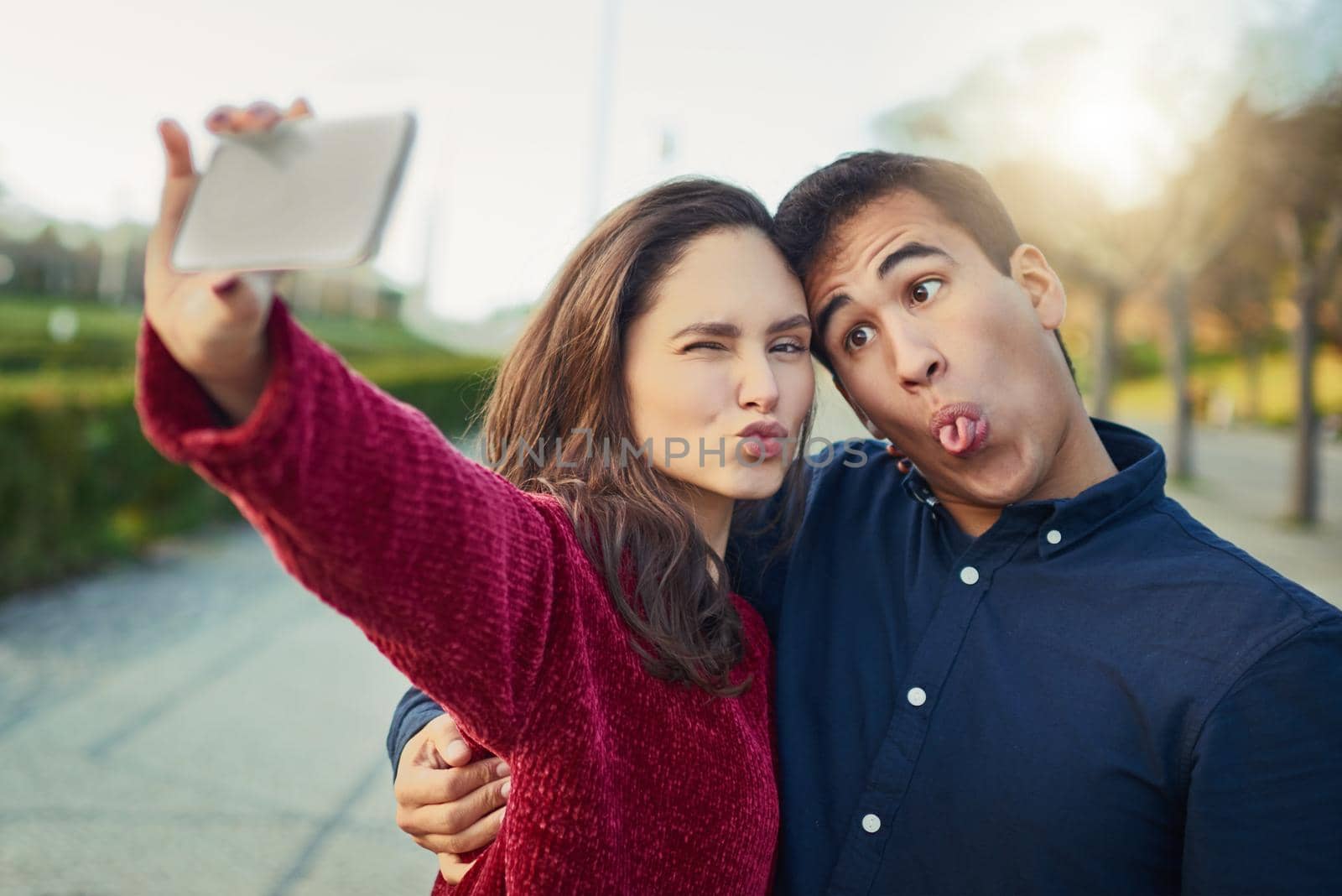 I found my soulmate in silliness. Shot of a young couple making funny faces while taking a selfie outdoors. by YuriArcurs
