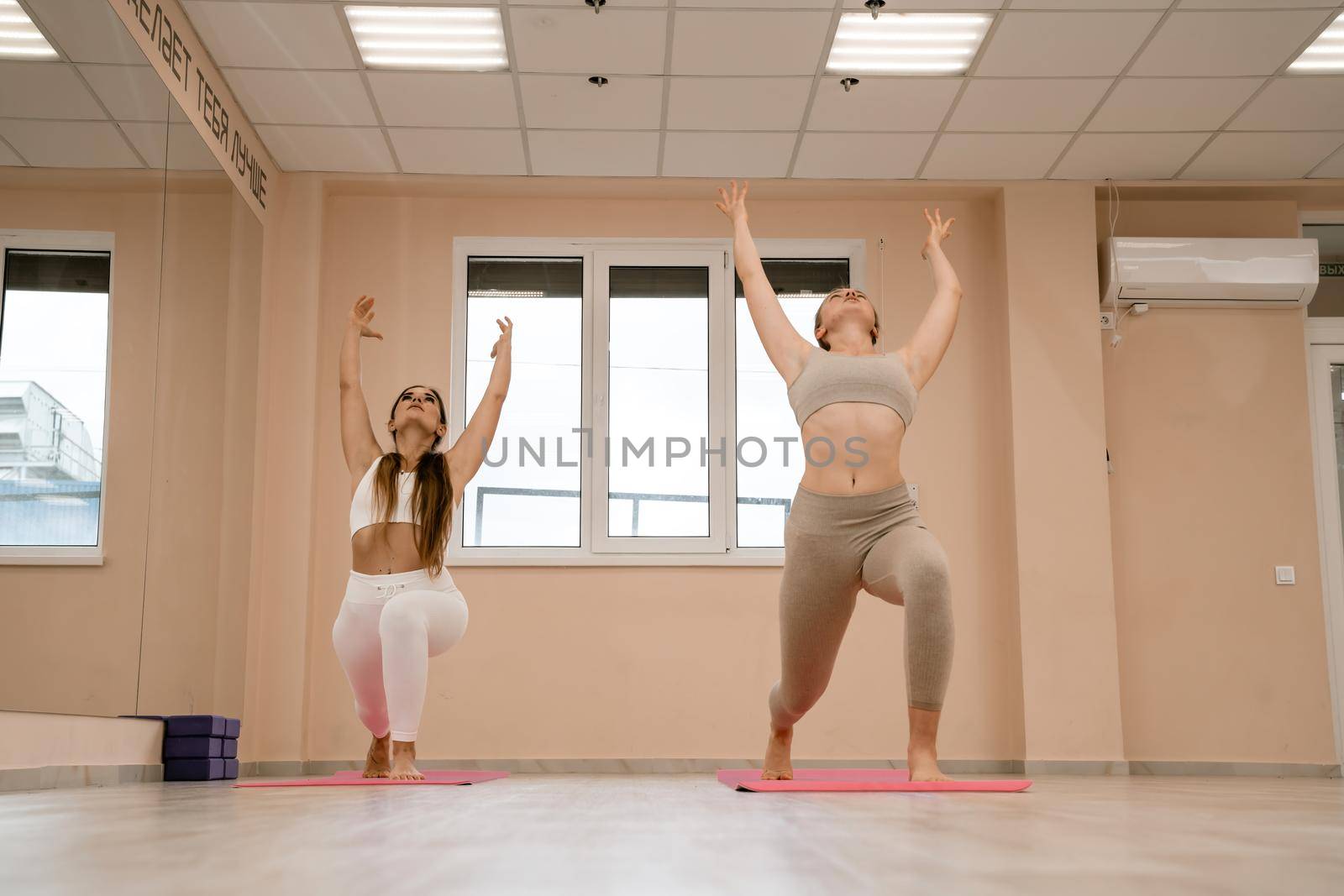 Two beautiful women do yoga, sports in the gym. The concept of grace and beauty of the body