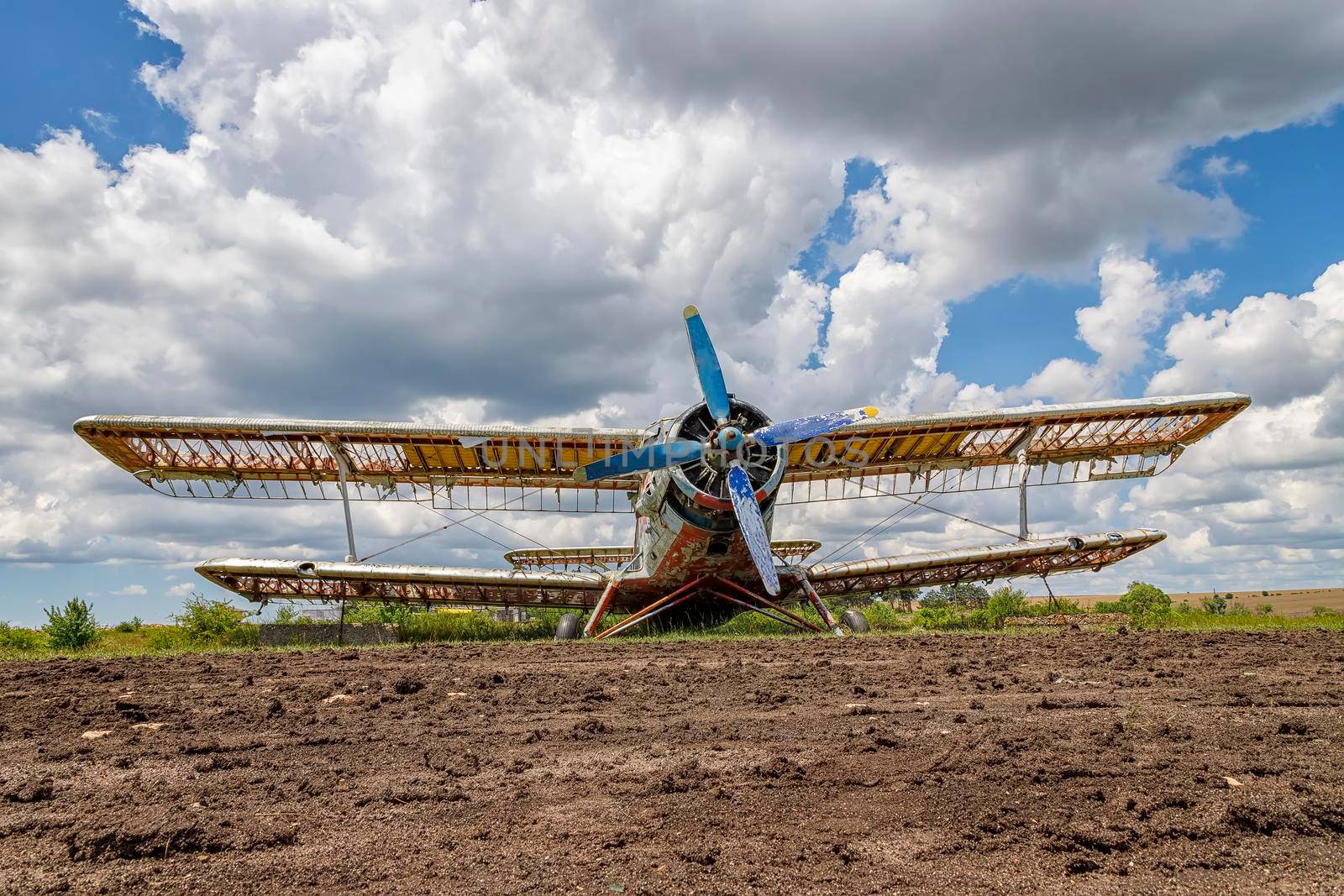 Abandoned aircraft plane standing in the field against the cloudy blue sky.  by EdVal