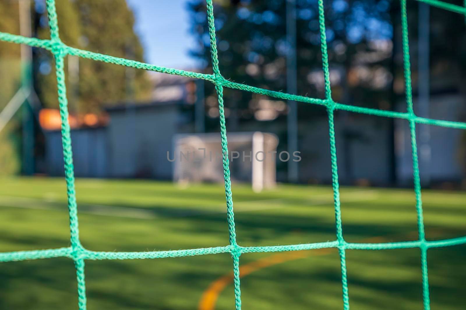 Green soccer net on a goal. Soccer net nodes. Blurred goal post in the background