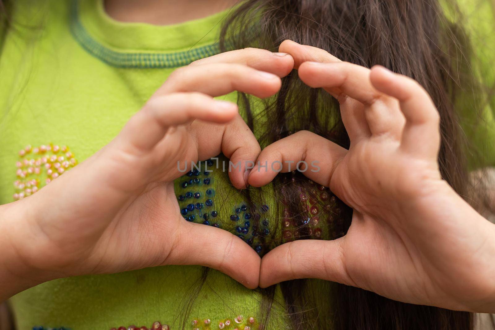 A cute Caucasian child holds a palm in the shape of a heart