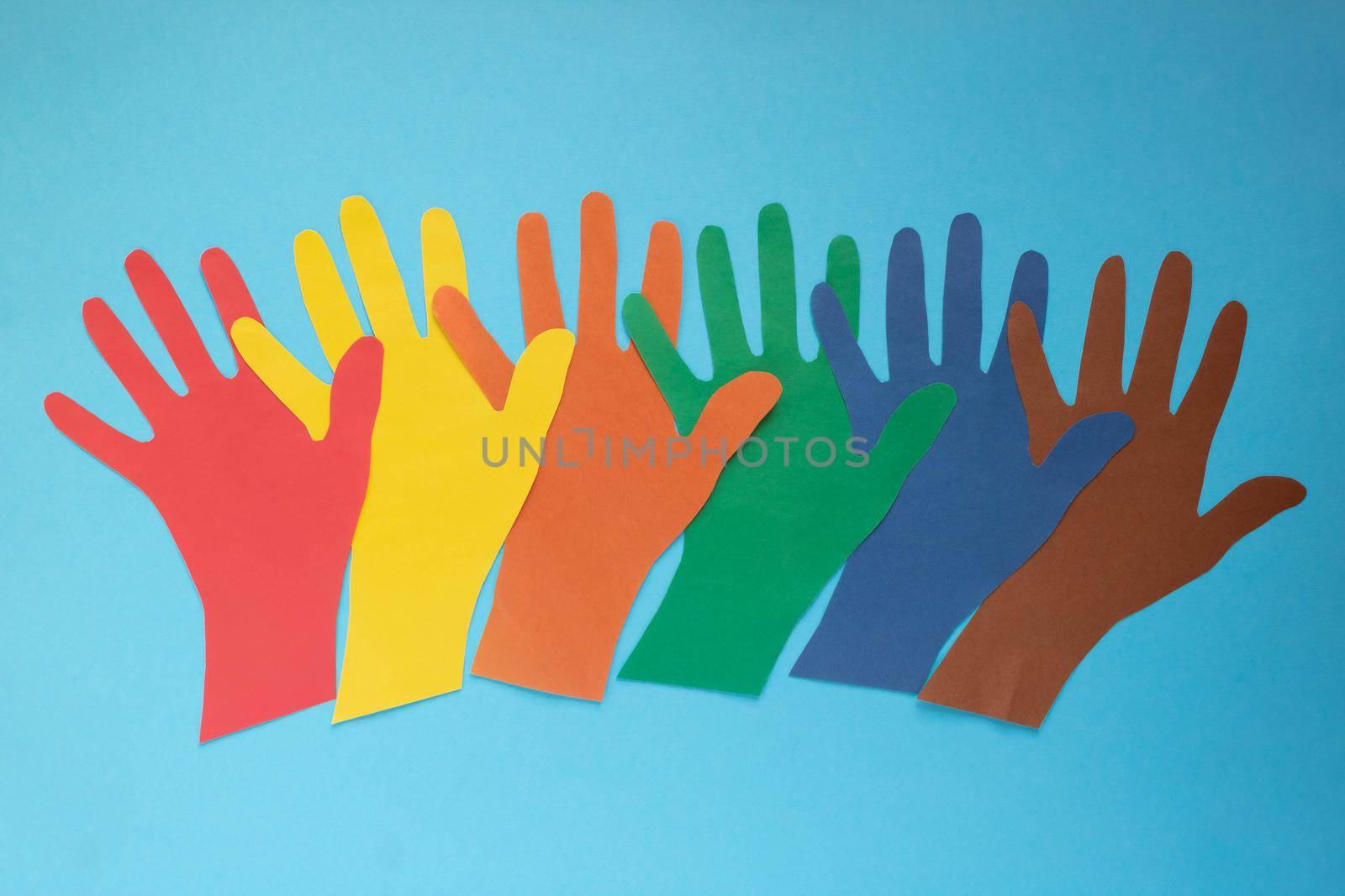 Abstract background open multicolored paper palms on a blue background.The concept of Autism Day and Youth Solidarity Day.