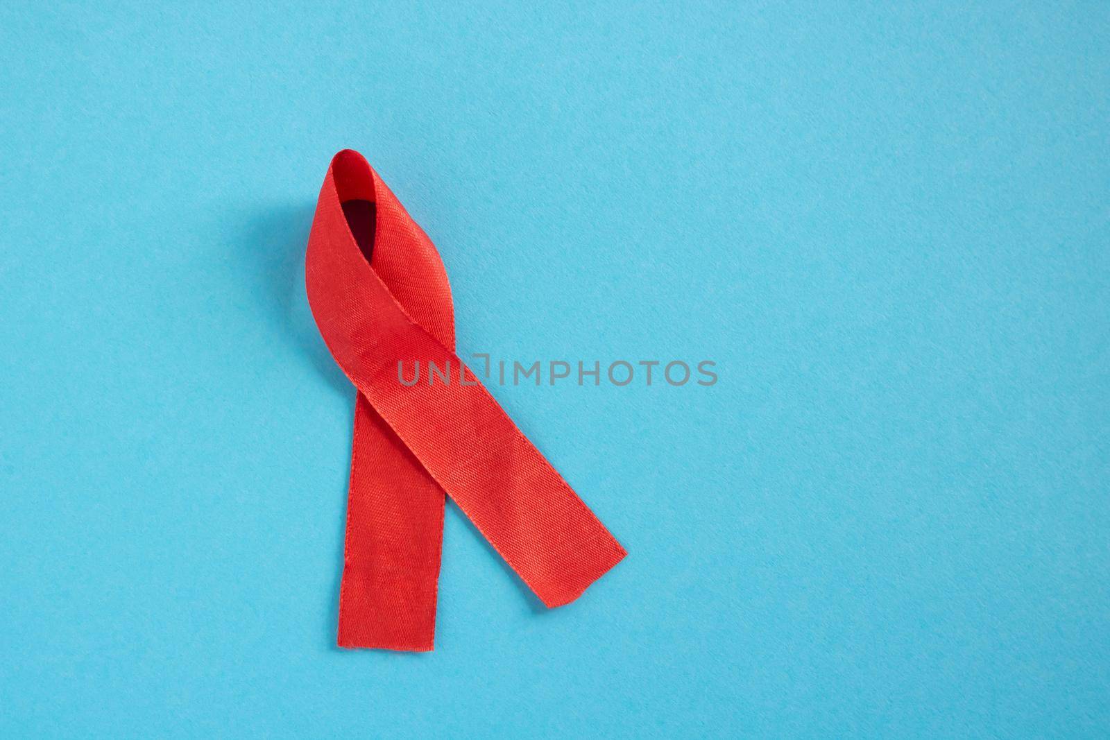 Red ribbon on a blue background the concept of World AIDS Day,Donor Day,Hemophilia Day. Place for your text by lapushka62