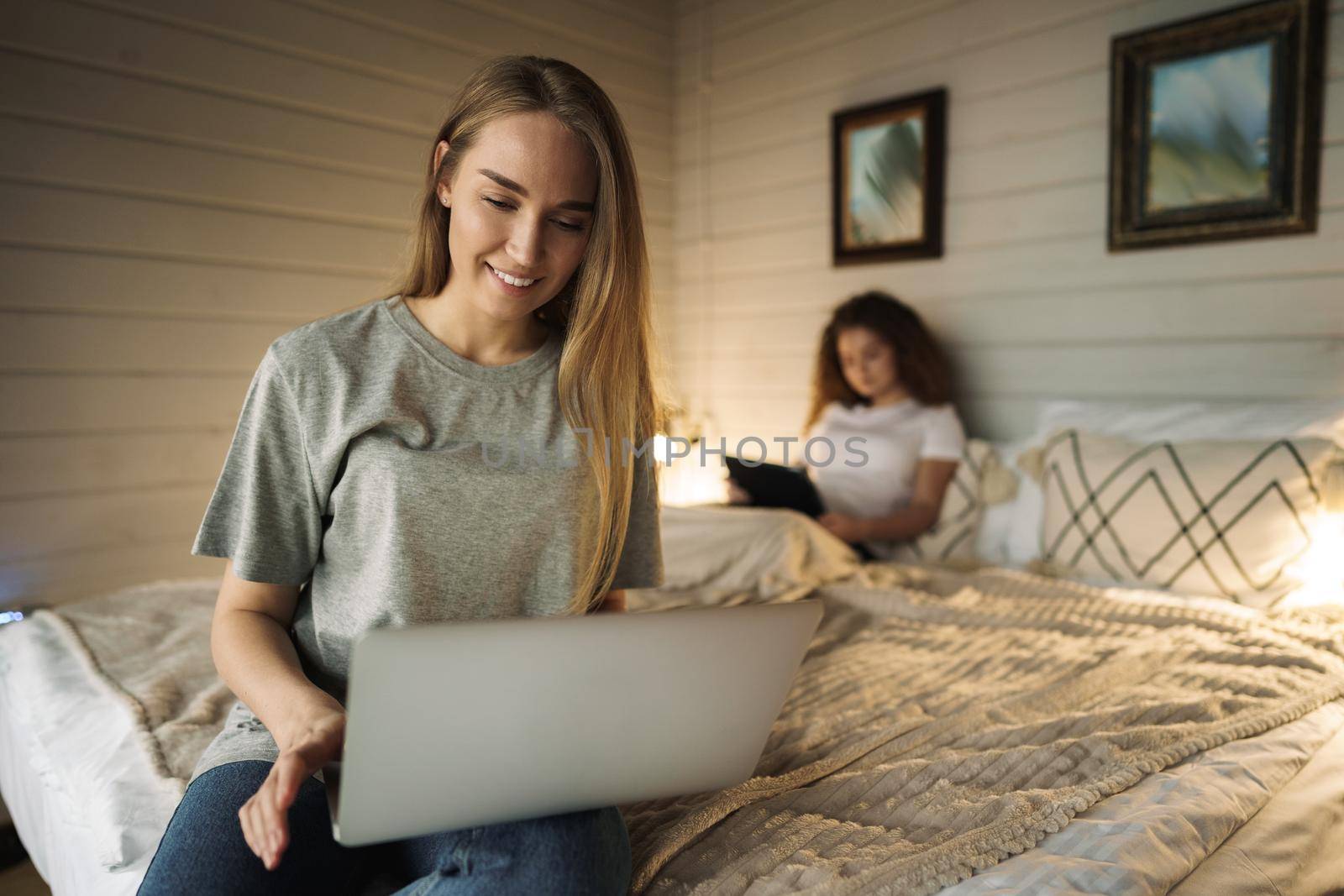 Two beautiful women lying in bed, holding and watching laptop