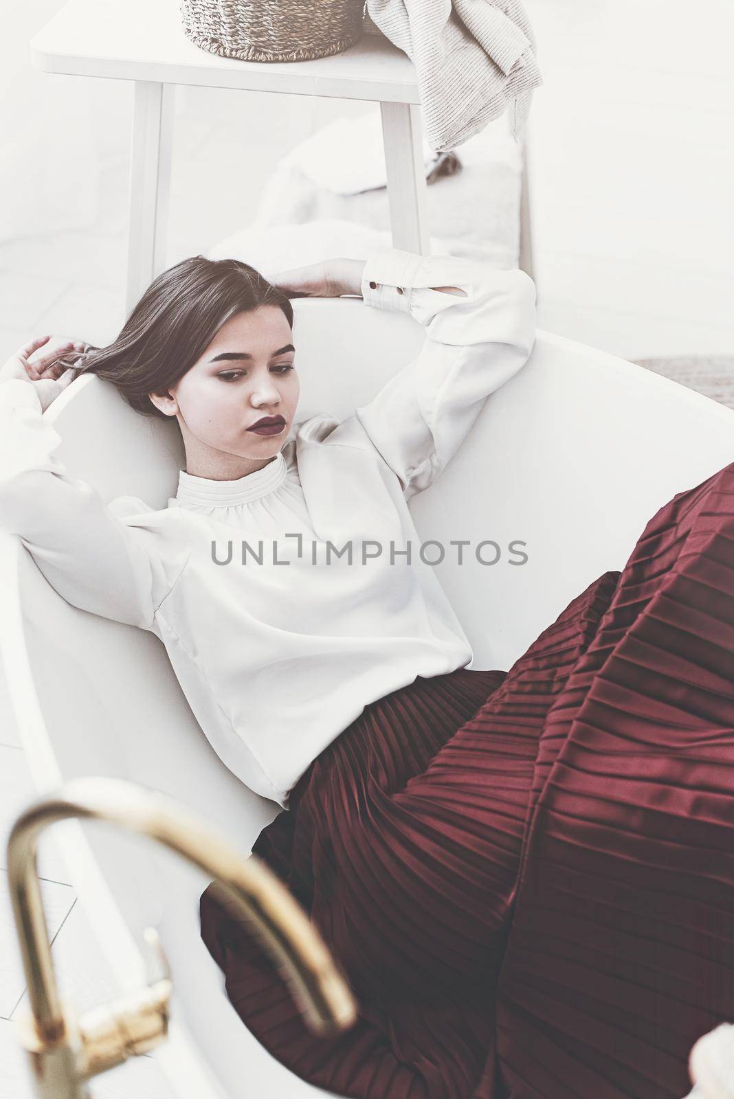 Portrait of fashionable women in red skirt and white blouse posing in a bath. Girl with a big red lips