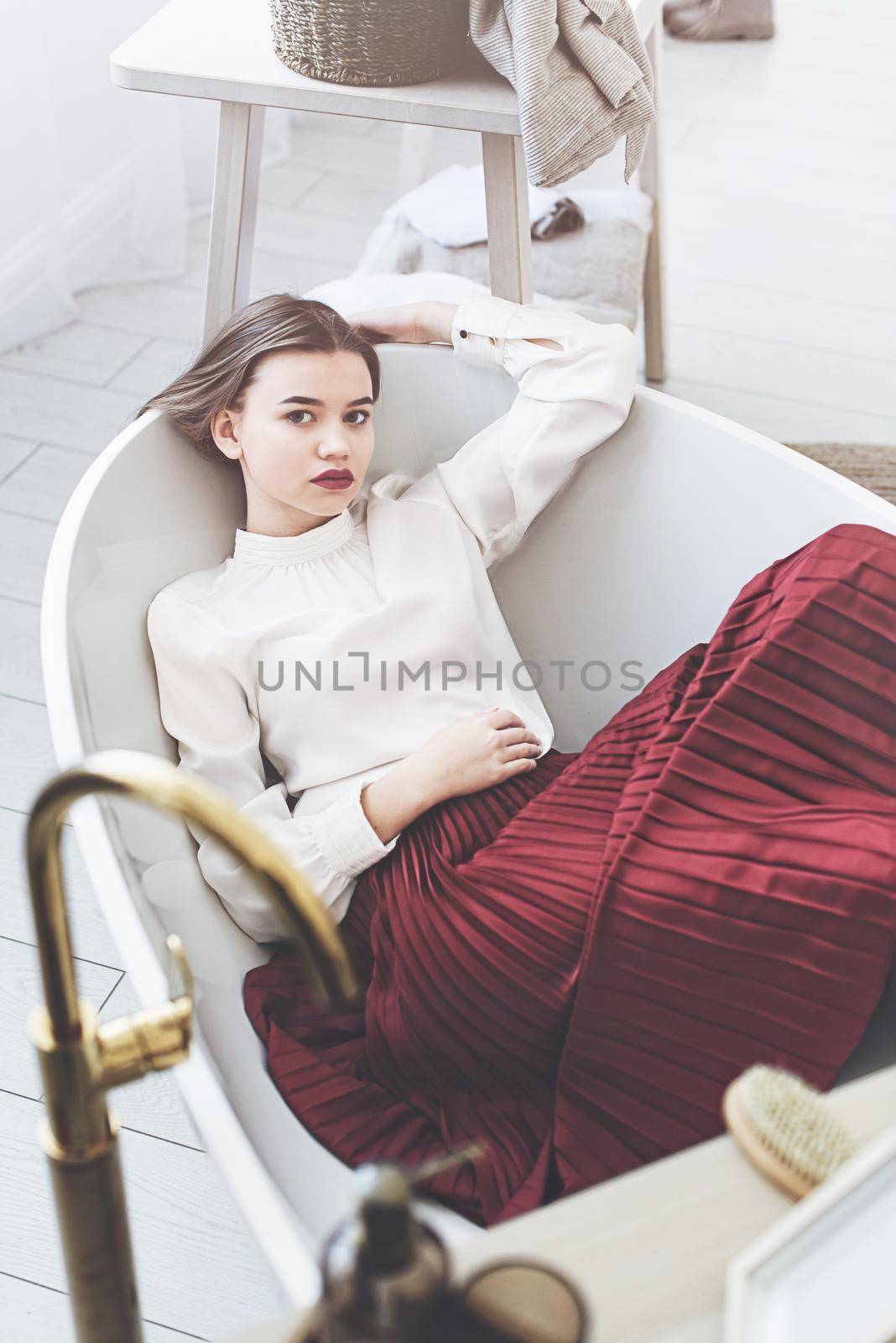 Portrait of fashionable women in red skirt and white blouse posing in a bath. Girl with a big red lips