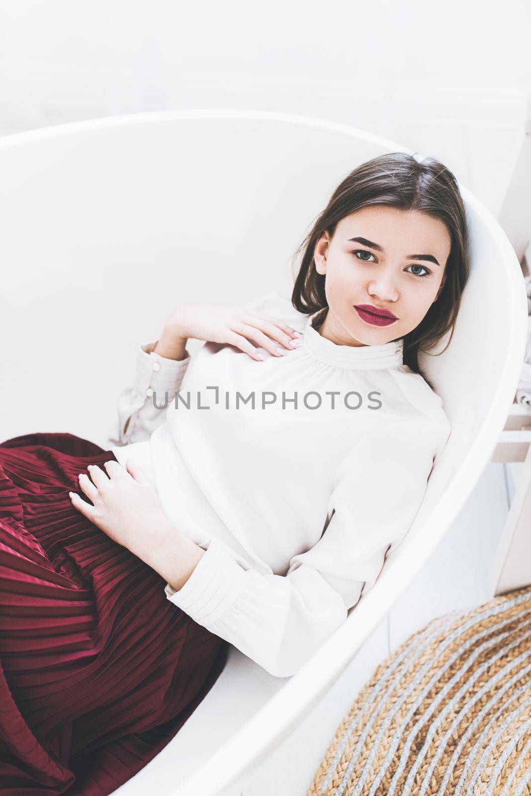 Portrait of fashionable women in red skirt and white blouse posing in a bath. Girl with a big red lips