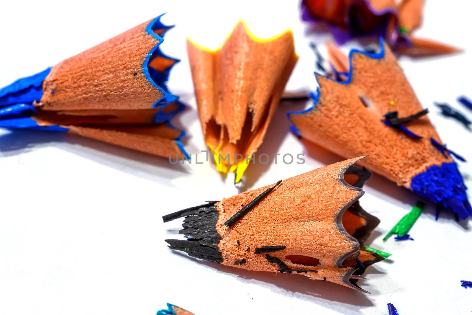 Wooden shavings of colored pencils on a white background. Fine shavings and pencil fragments