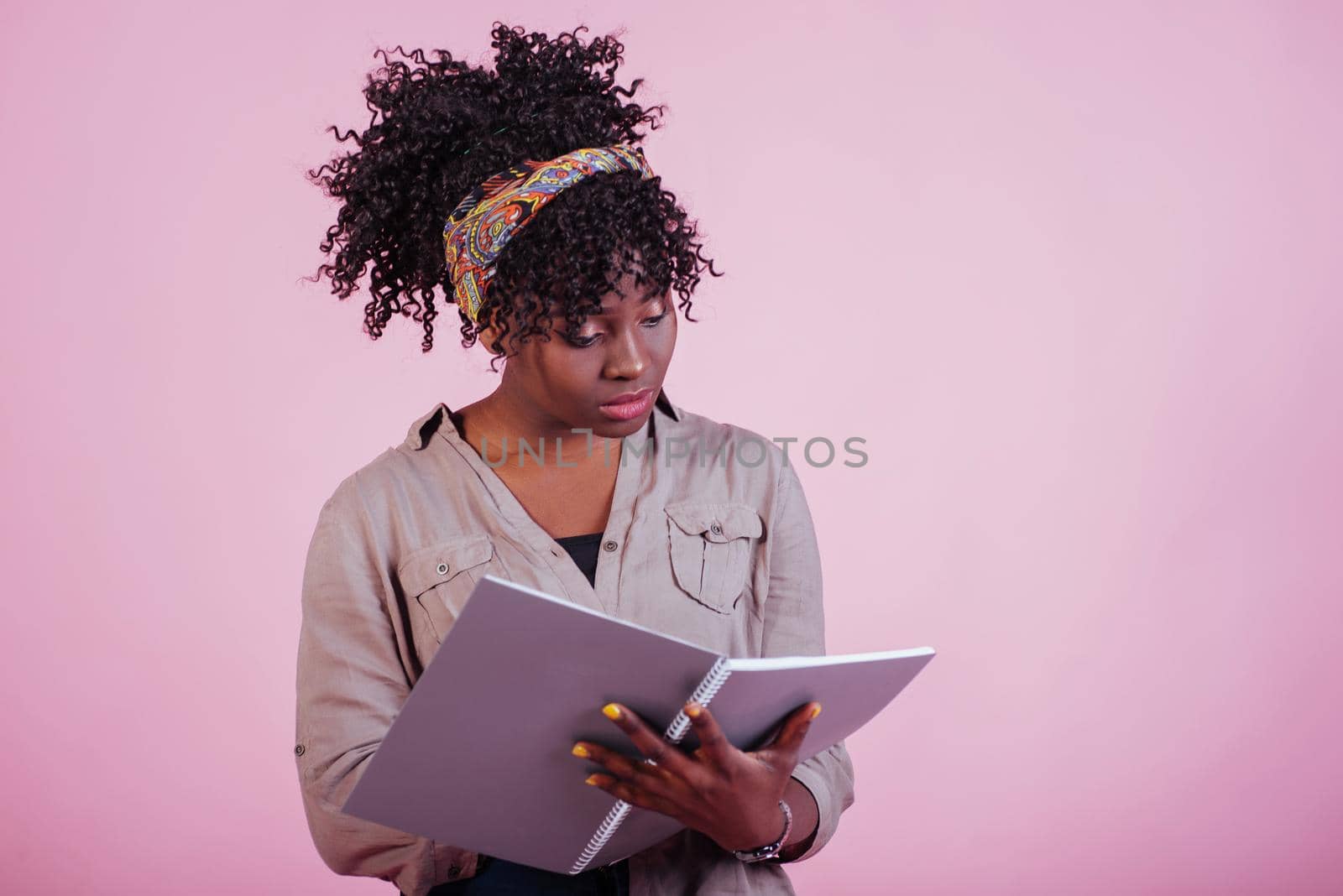 Preparing for exam. Attractive afro american woman in casual clothes at pink background in the studio.