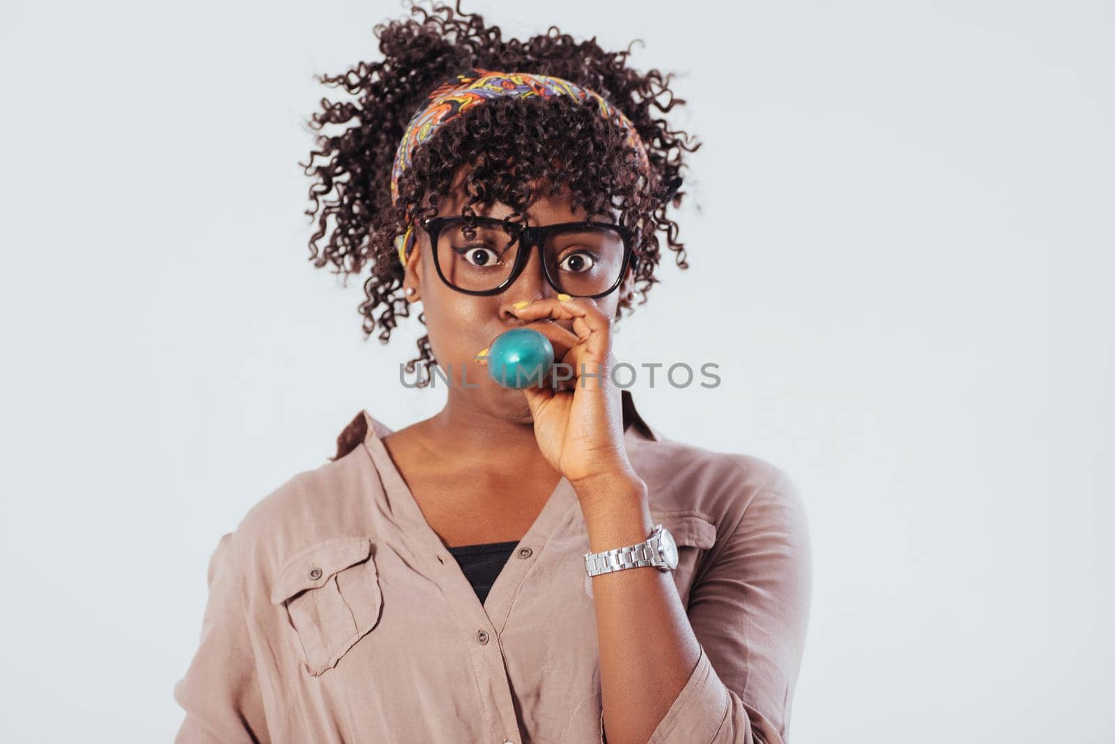 Inflates a blue ball. Beautiful afro american girl with curly hair in the studio with white background.