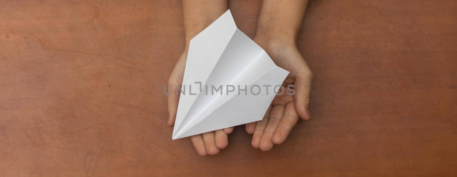 Child's Dream. Child's hand launching white paper airplane.
